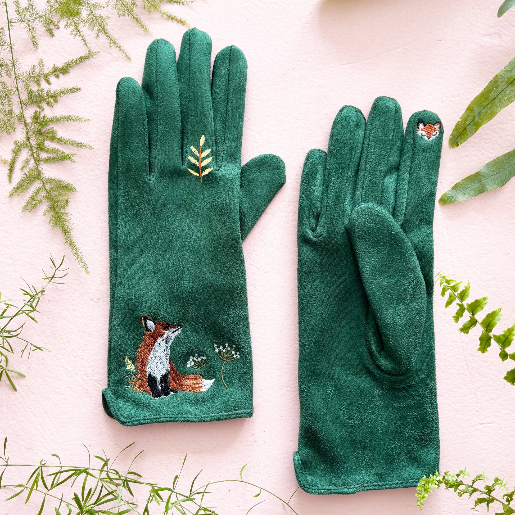 Green suedette fox gloves with embroidered wildflower detail on pink background