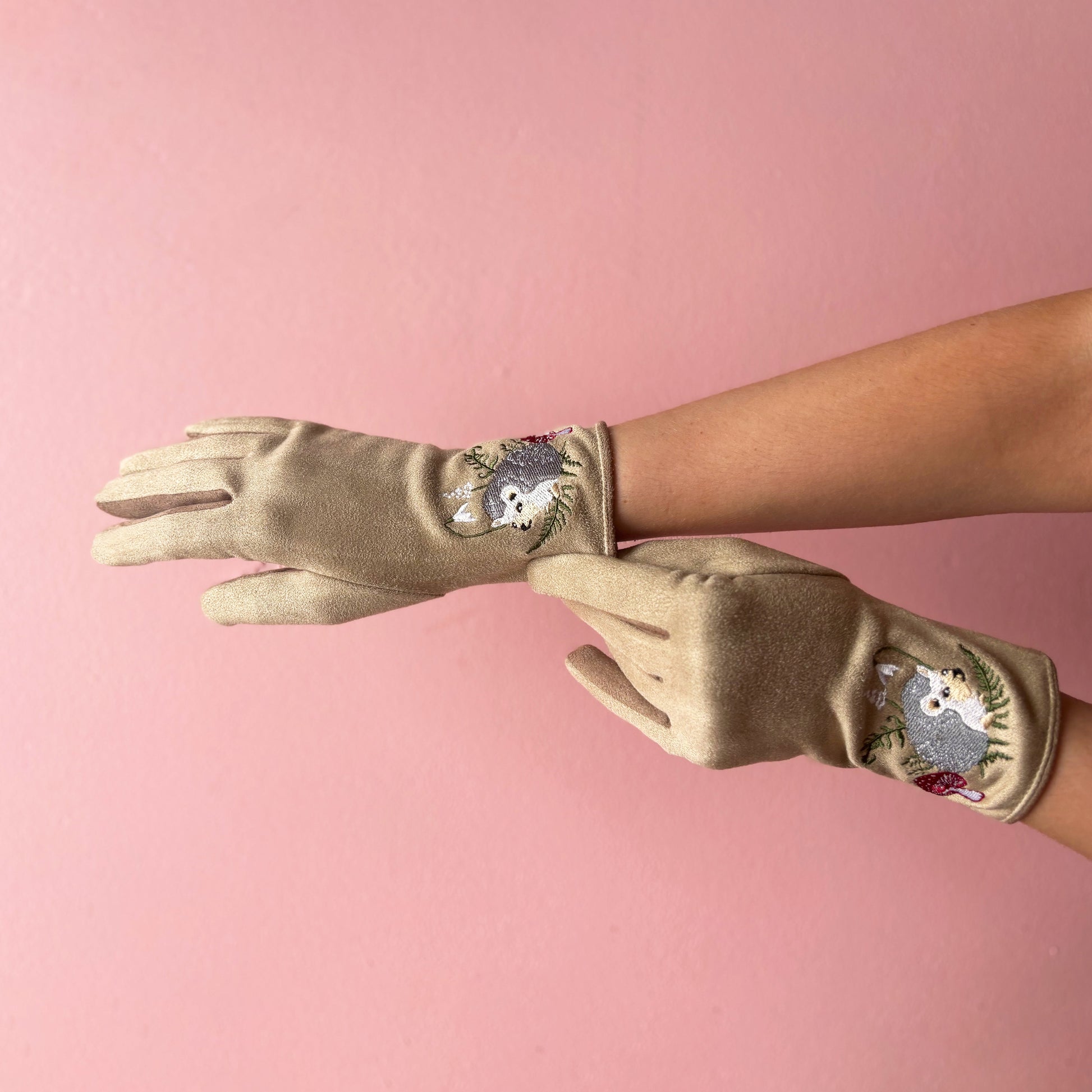 Hedgehog gloves worn on hands showing embroidered front on pink background