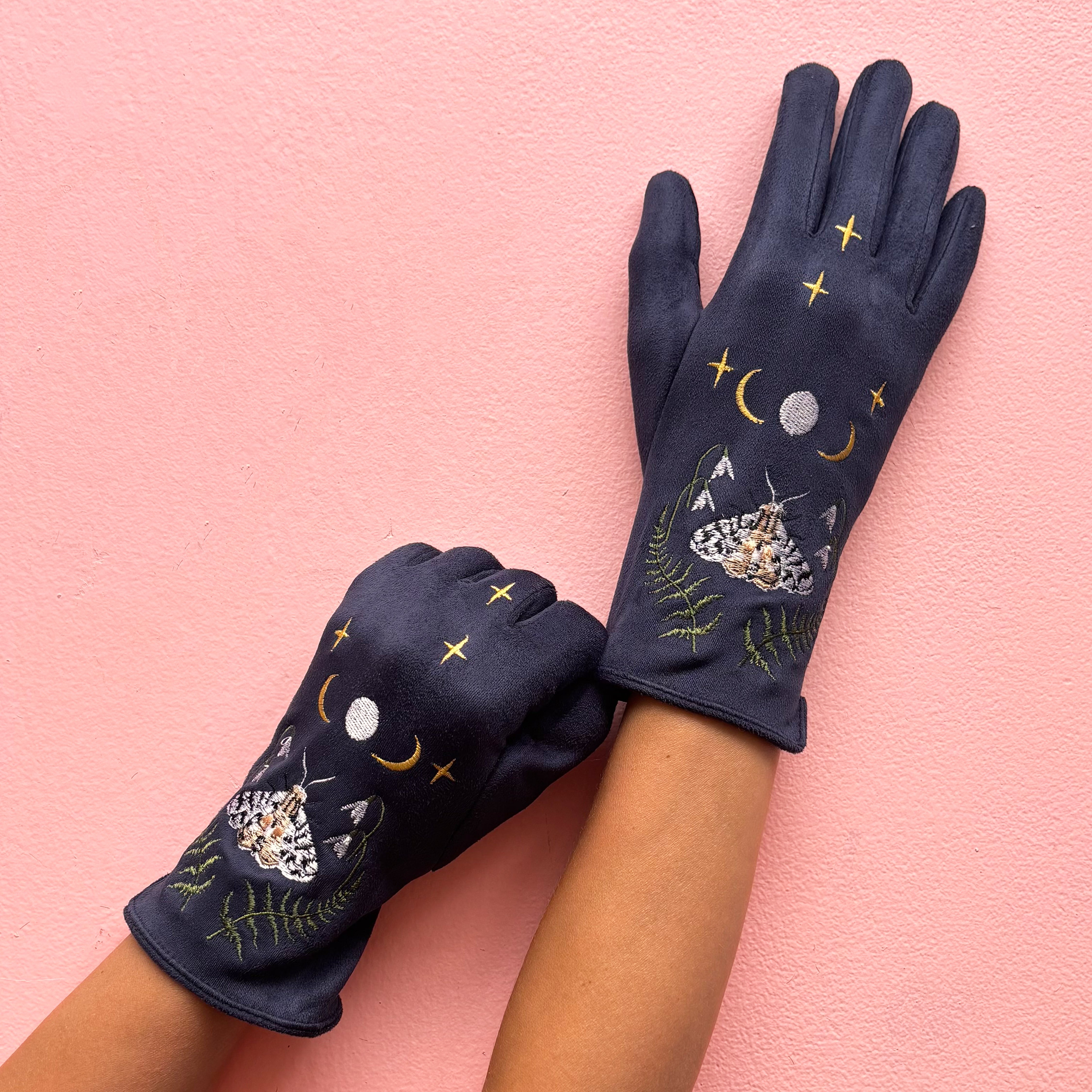 Close-up of moth embroidery with moon and stars on navy glove