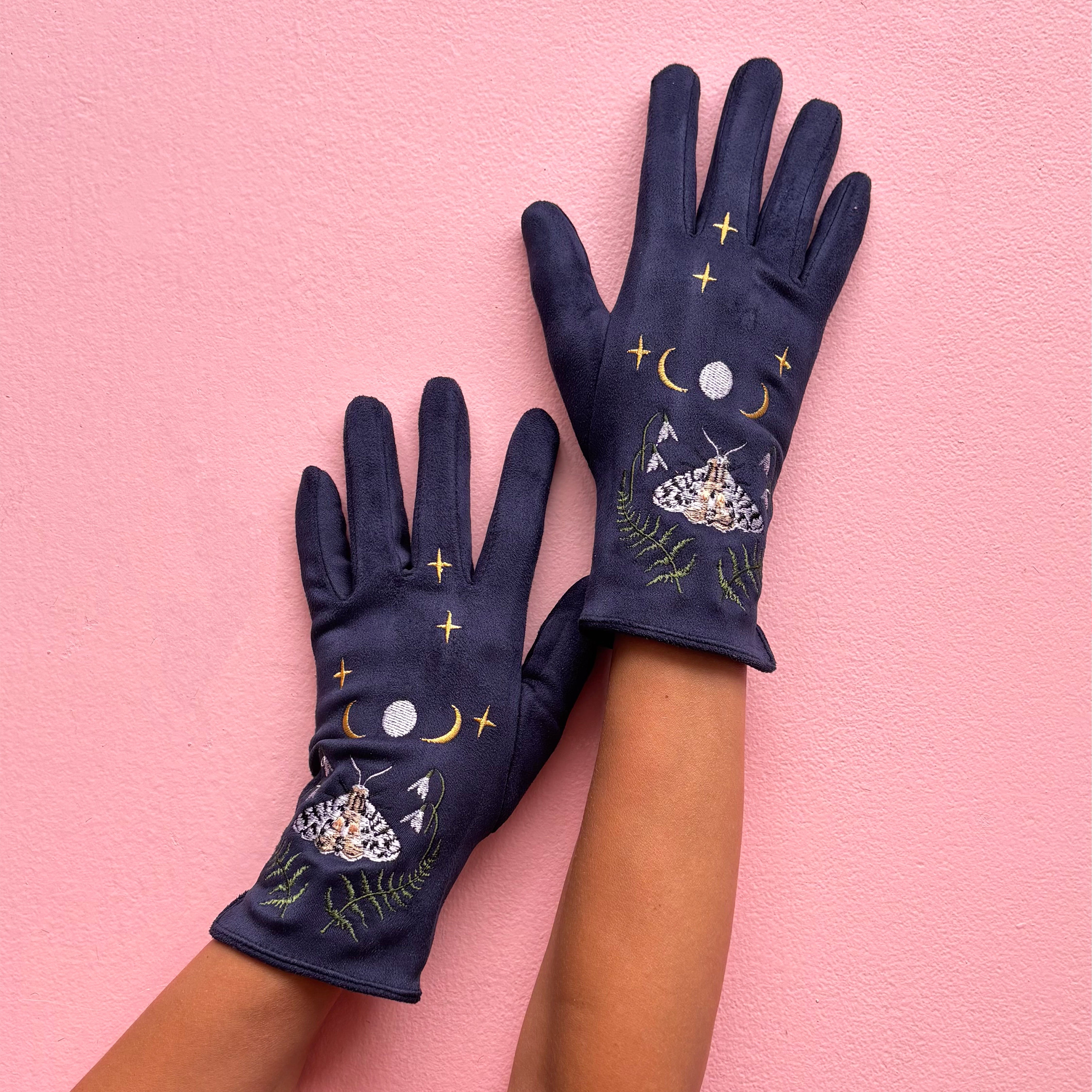 Navy embroidered moth gloves worn on hands showing celestial design on pink background