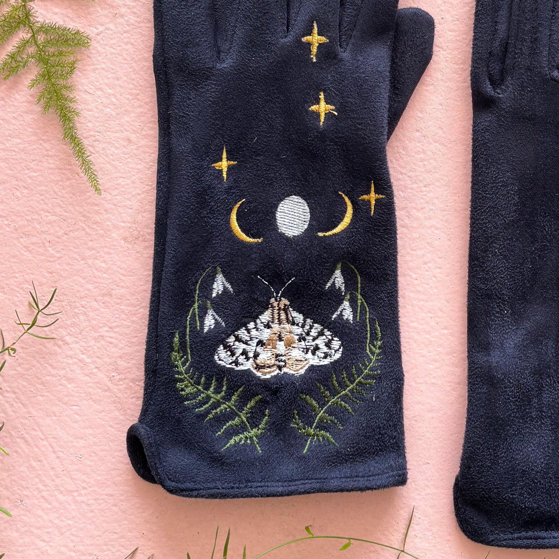 Detail of embroidered moth with crescent moon and fern leaves on navy suedette