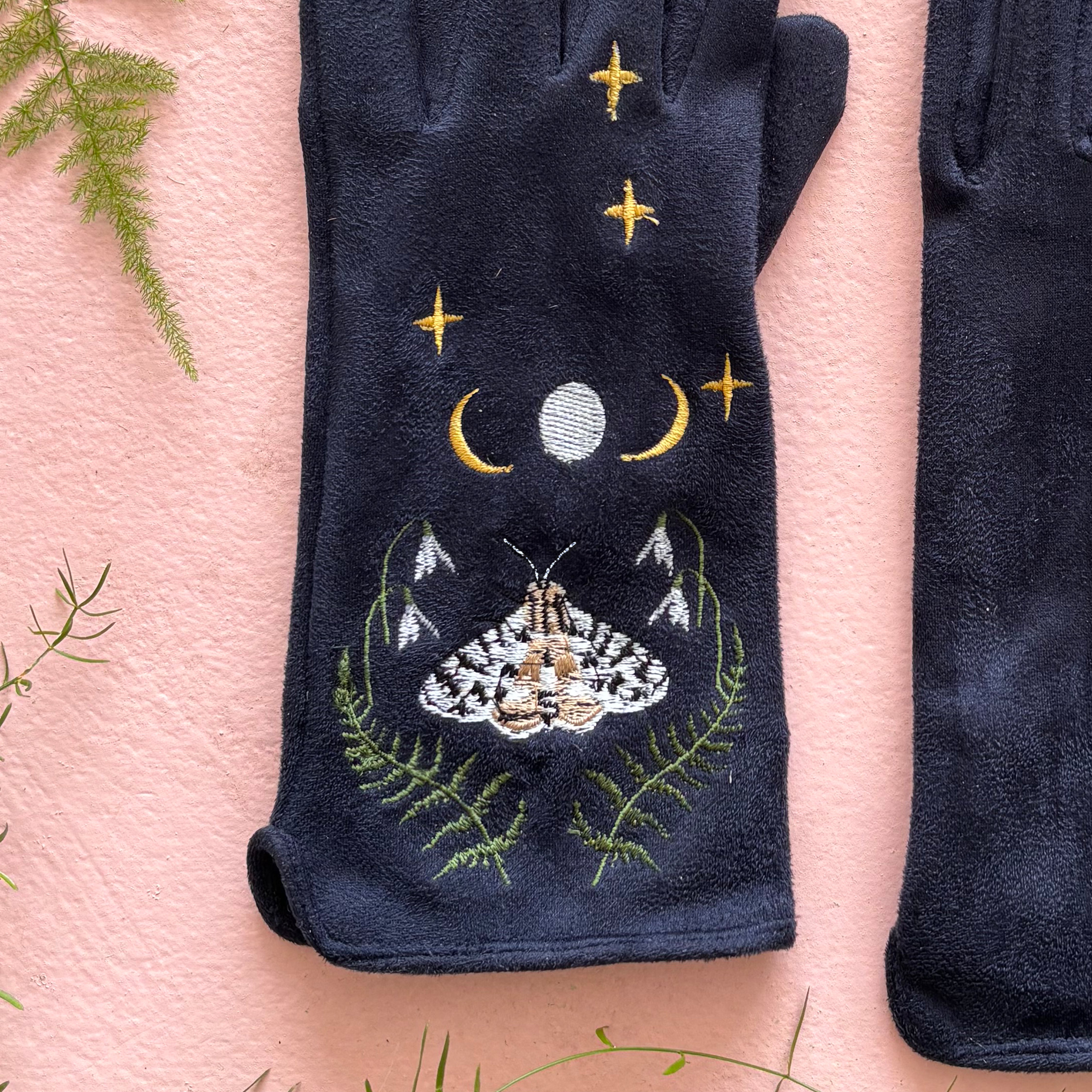 Detail of embroidered moth with crescent moon and fern leaves on navy suedette
