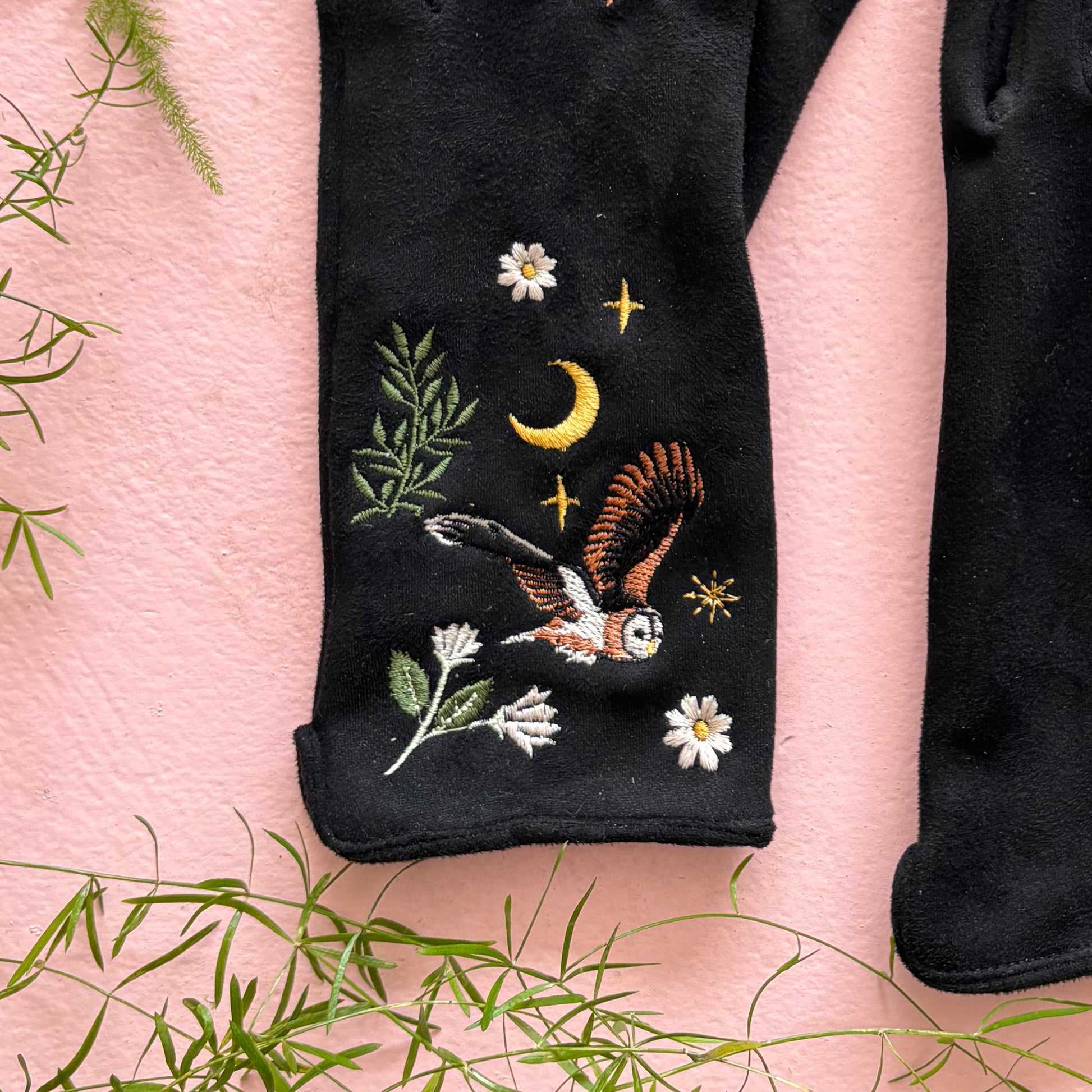 Close-up of embroidered barn owl with moon and daisies on glove cuff