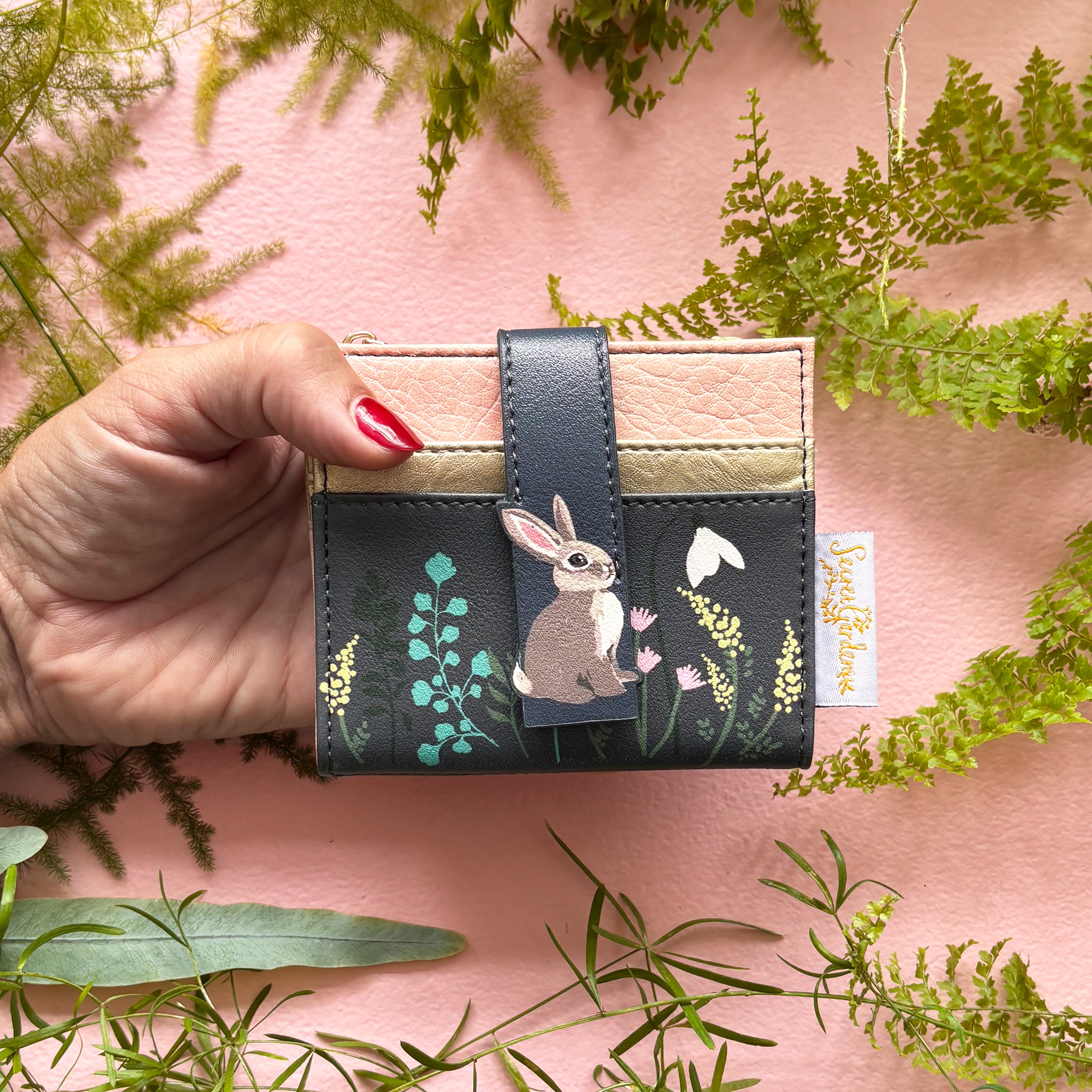 Secret Garden rabbit purse held in hand on pink background with ferns