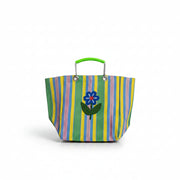 A person wearing a white long-sleeve top and blue jeans holds a striped tote bag with a green handle and a blue flower applique on the front, against a plain light gray background.