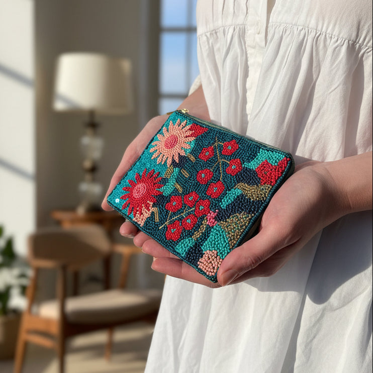 Teal beaded purse with pink floral design held in hand