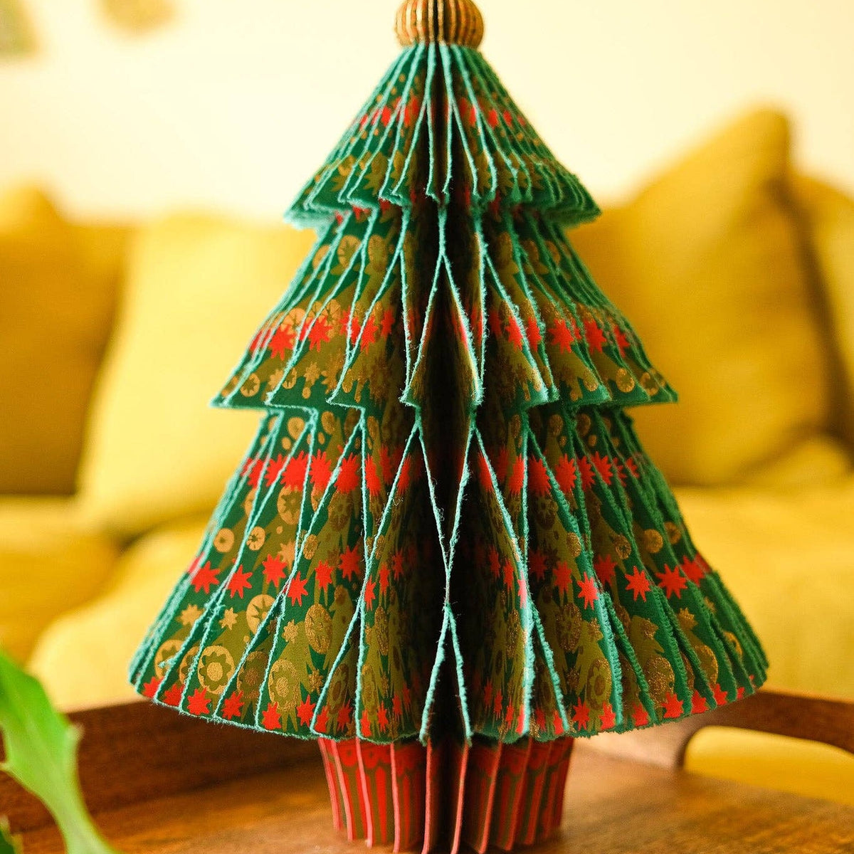 Fir Tree Honeycomb decoration in green, red and gold standing on a wooden table