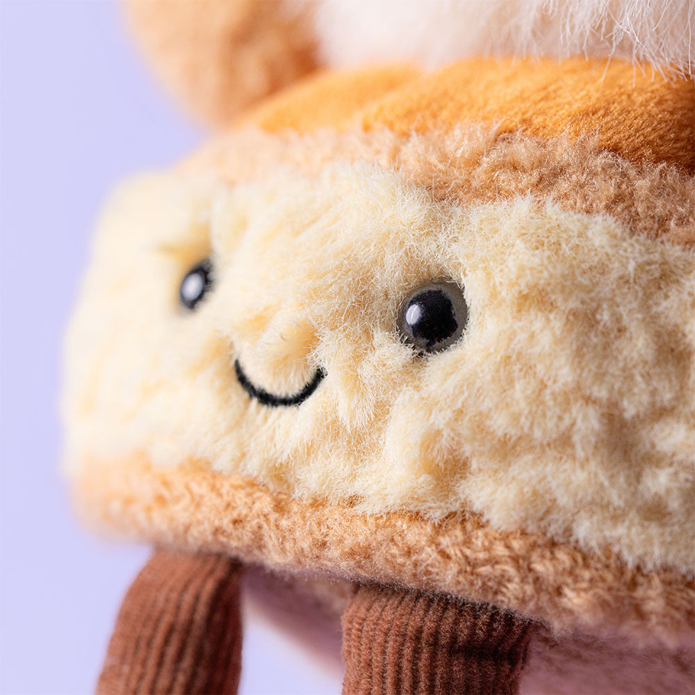 Close-up of Jellycat Mirielle St Honore smiling face on lilac background
