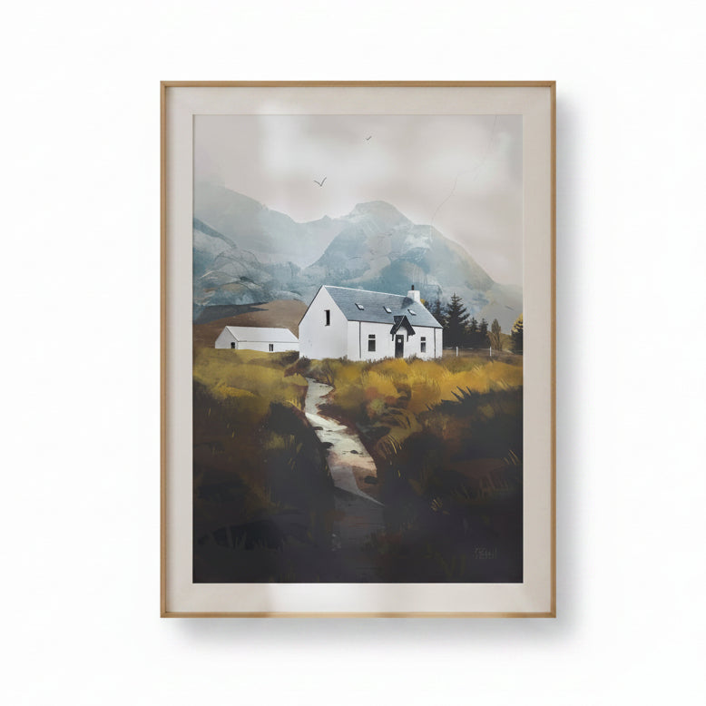 A framed landscape art print depicting a white cottage with a gray roof nestled in a grassy valley with mountains in the background, enclosed in a light wood frame.
