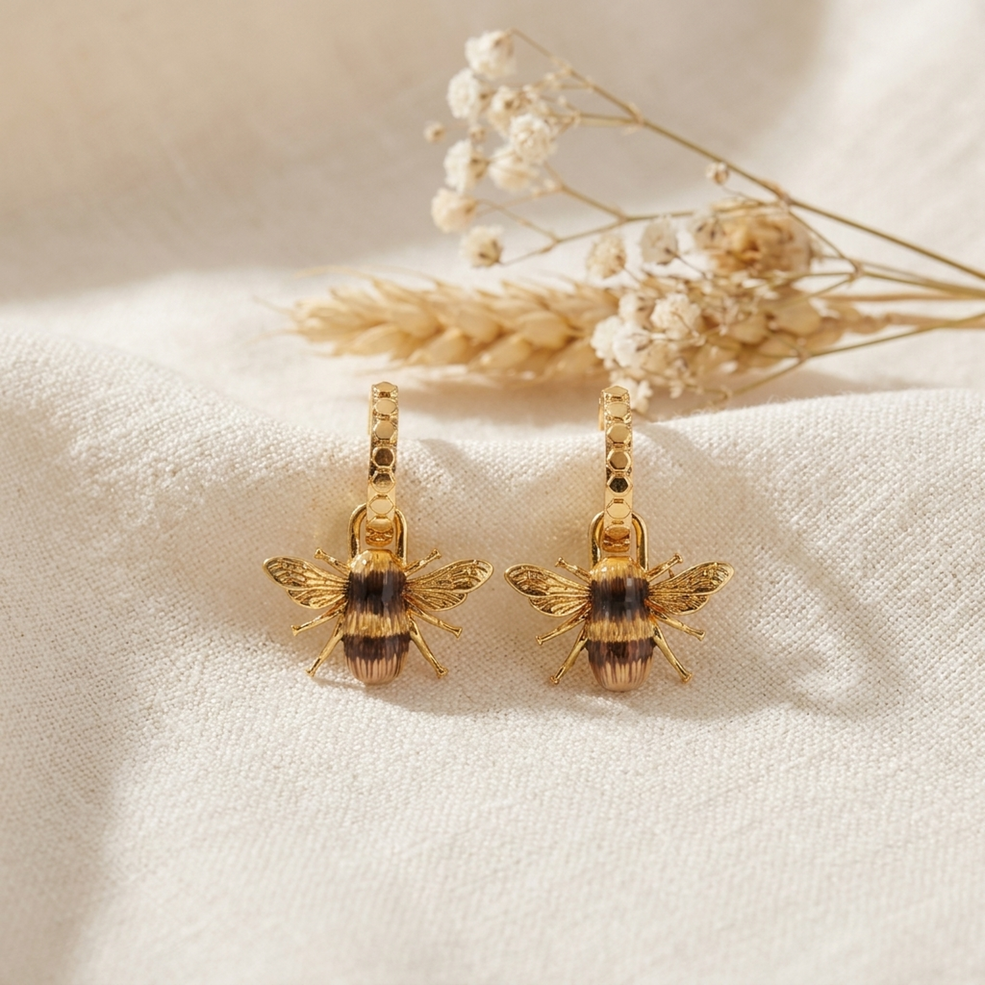 Bee Huggie Earrings styled on cream linen with dried flowers