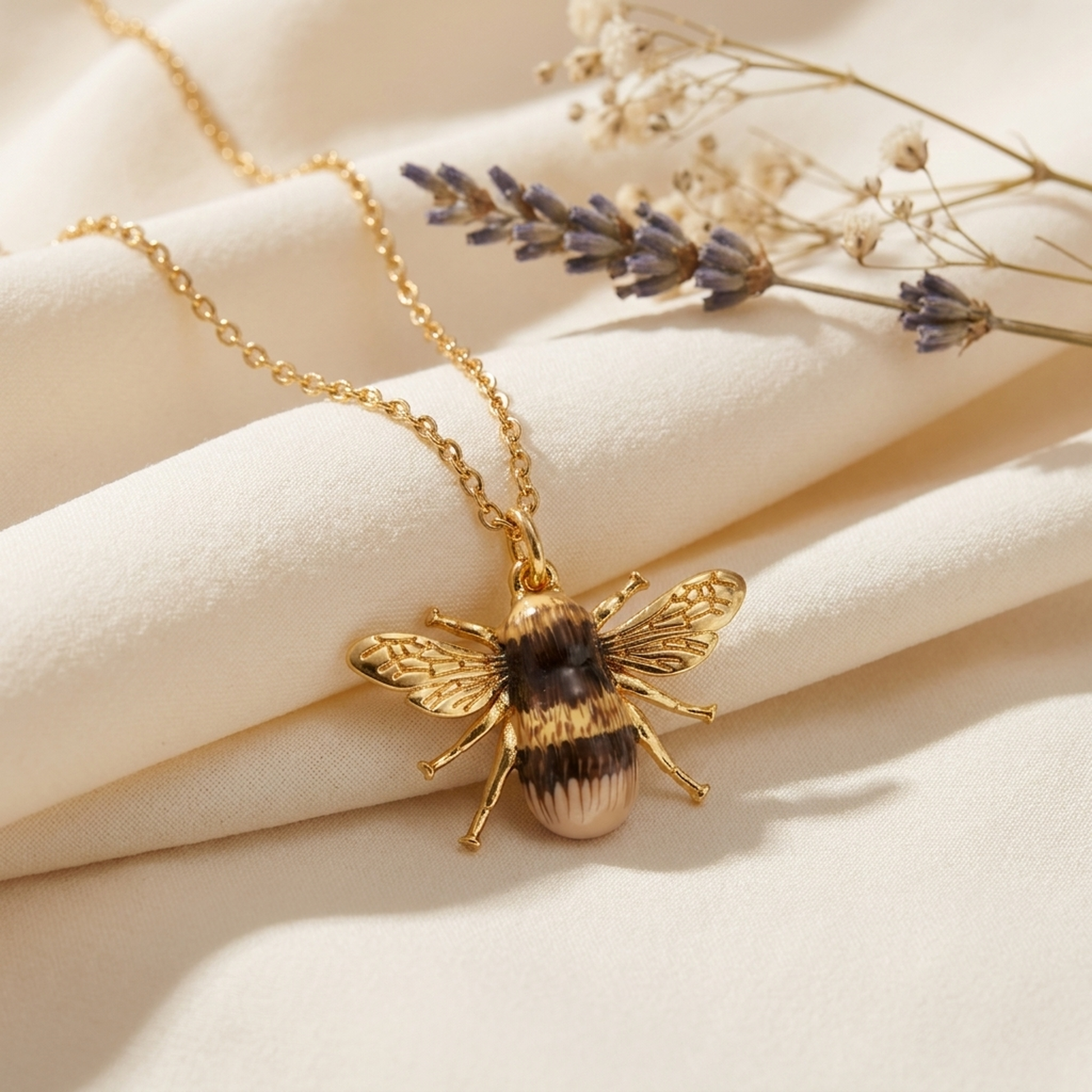 Bee Necklace draped on soft cream fabric with dried flowers