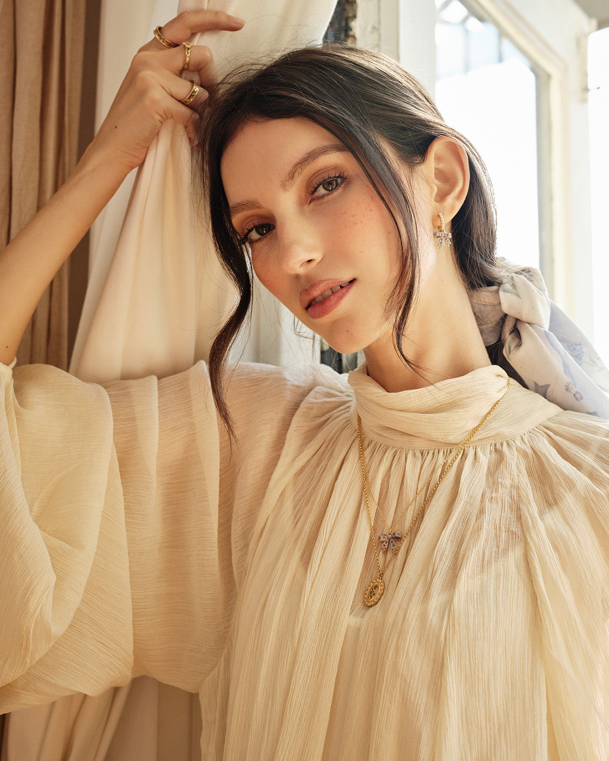 Model wearing the Fable England enamel bow pendant necklace with a cream blouse