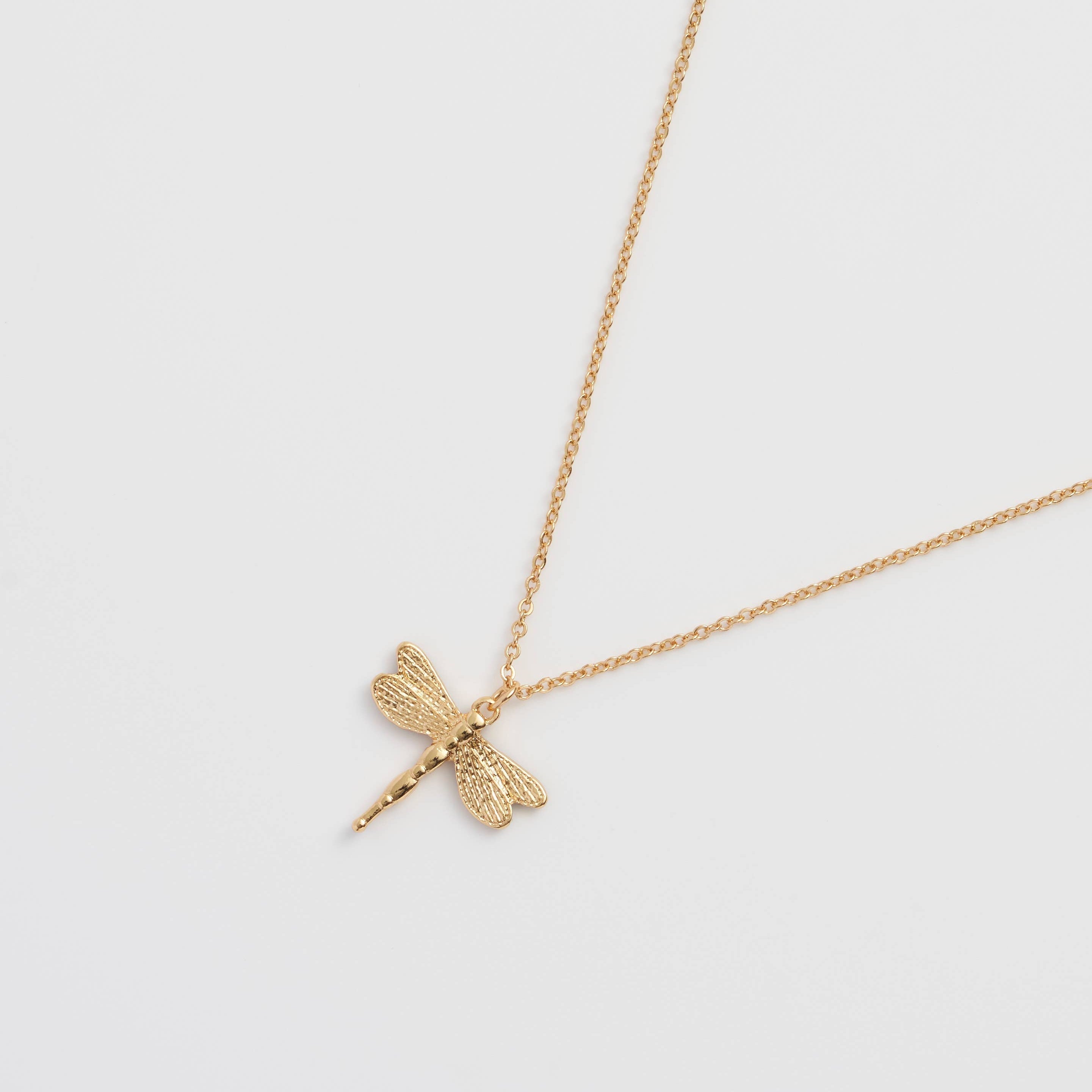 Dragonfly pendant reverse in plain gold showing textured wings on white background