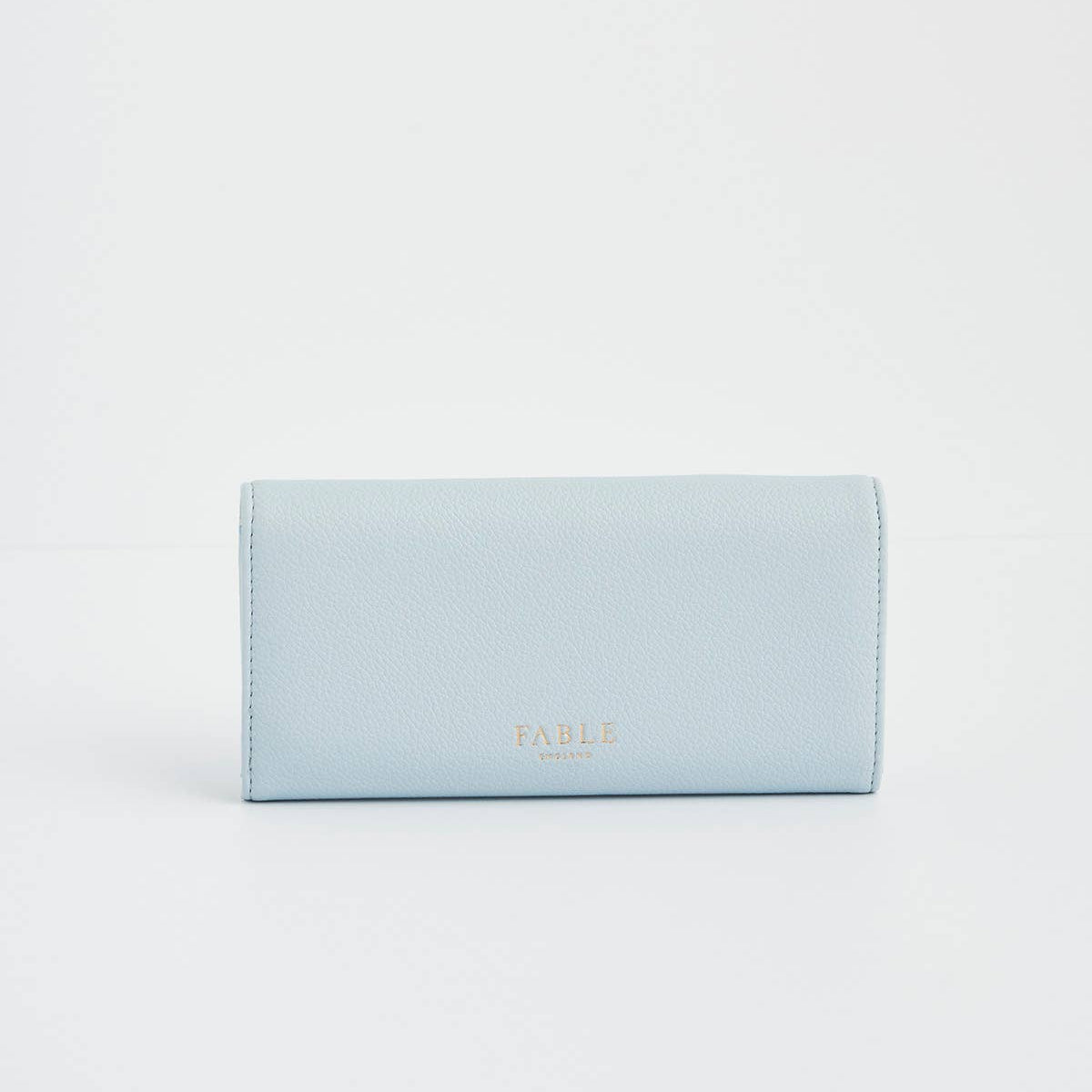 Gold Fable England logo stamped on light blue pebbled faux leather.