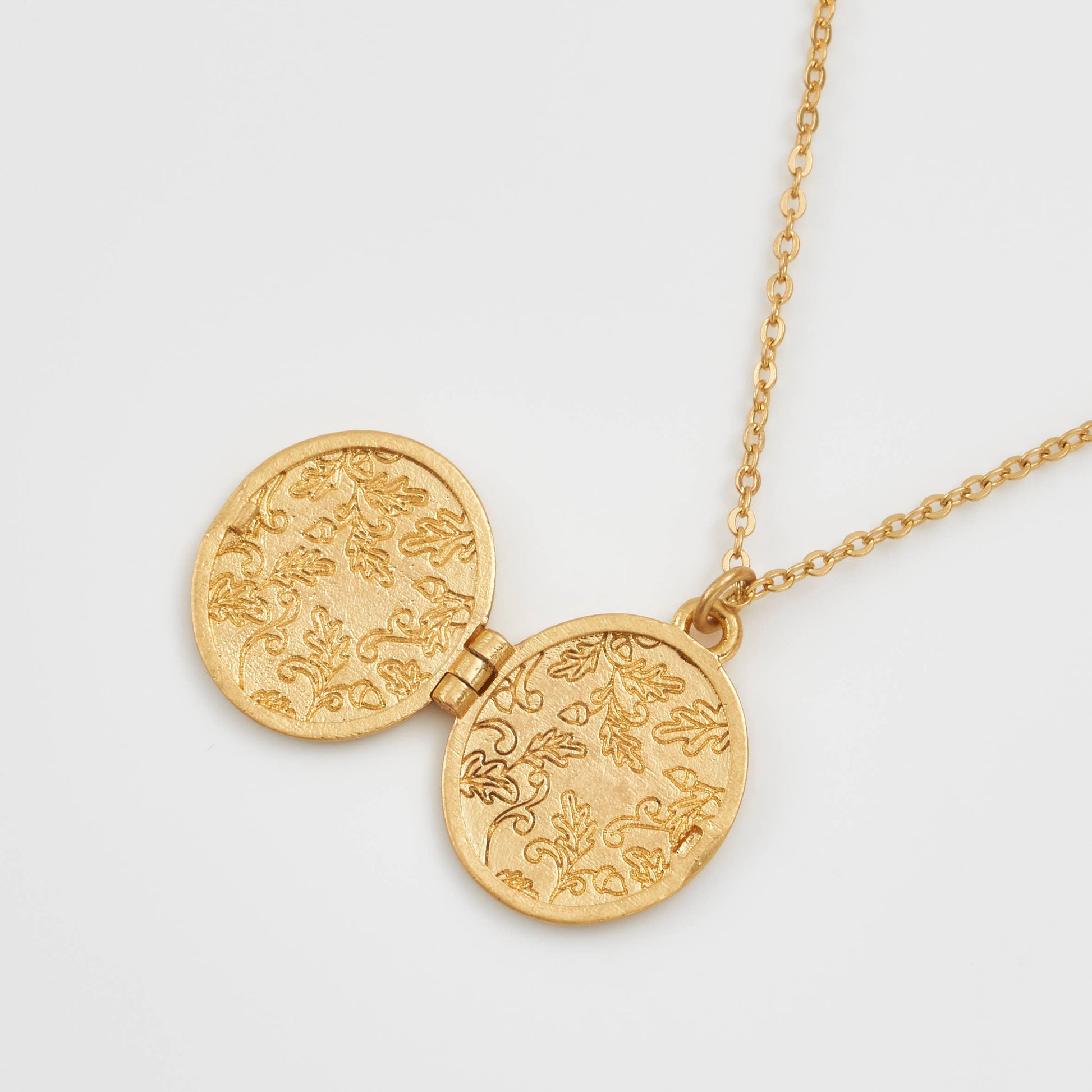 Running bunny locket open showing engraved oak leaf interior on white