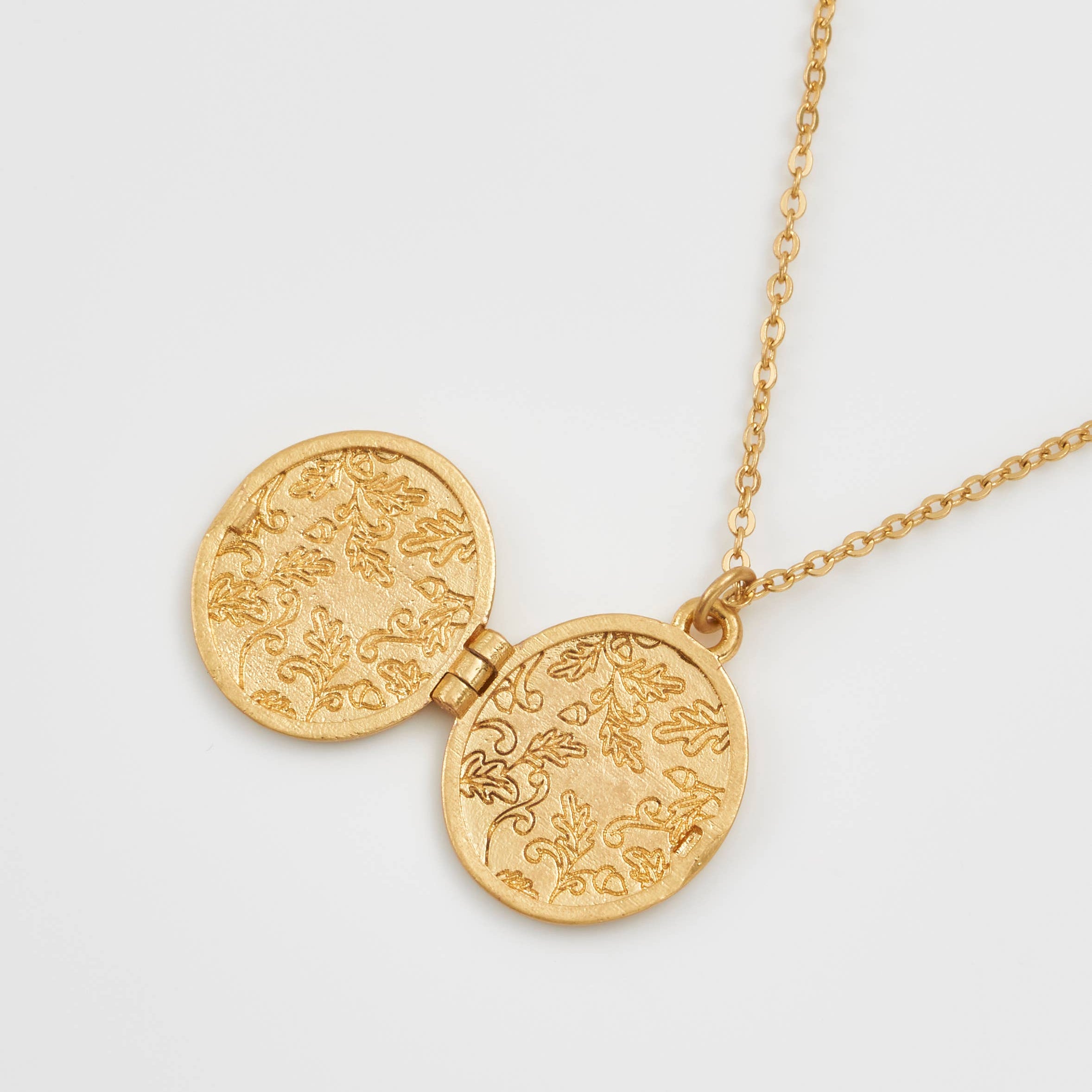 Running bunny locket open showing engraved oak leaf interior on white
