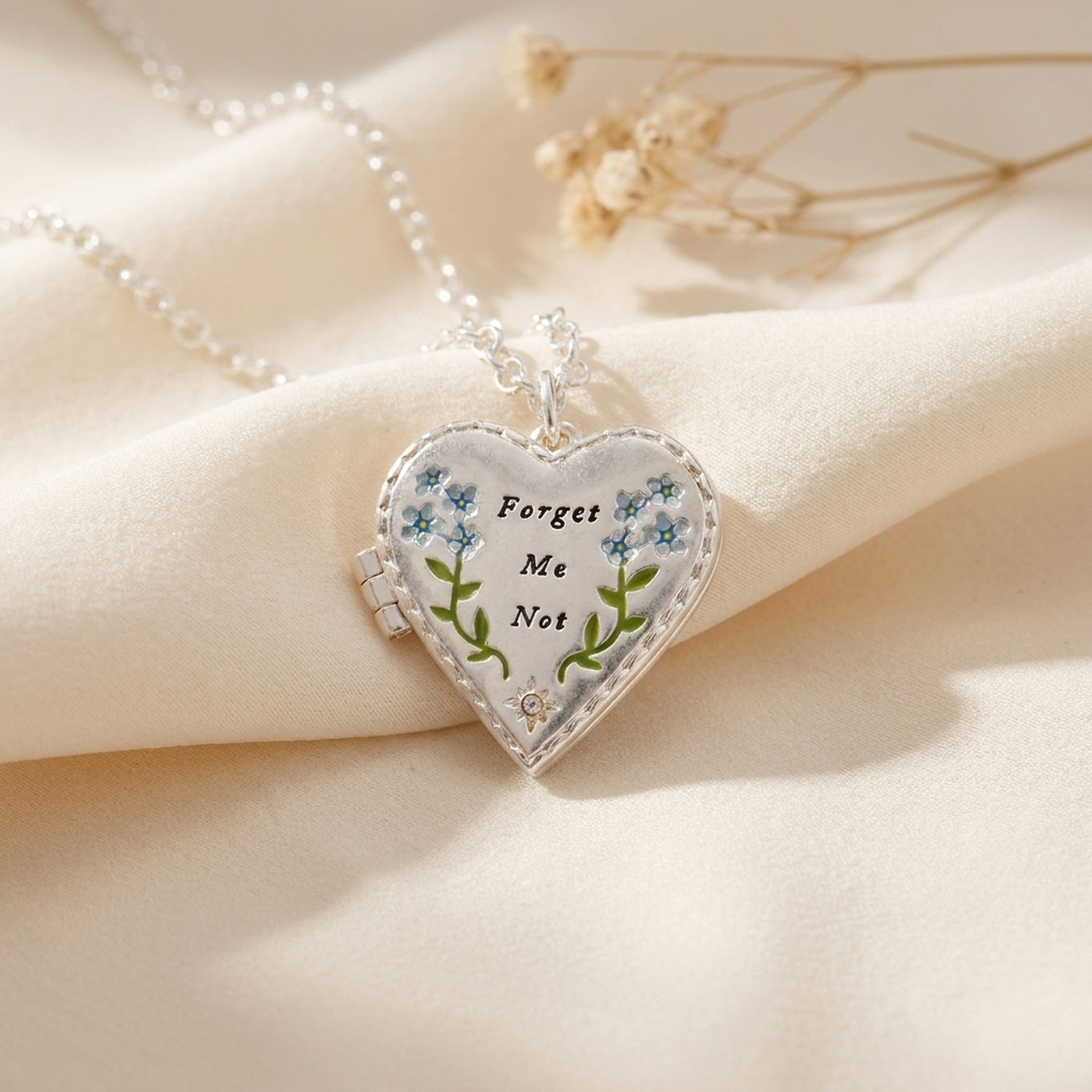 Floral Heart Silver Locket Necklace draped on soft cream fabric with dried flowers