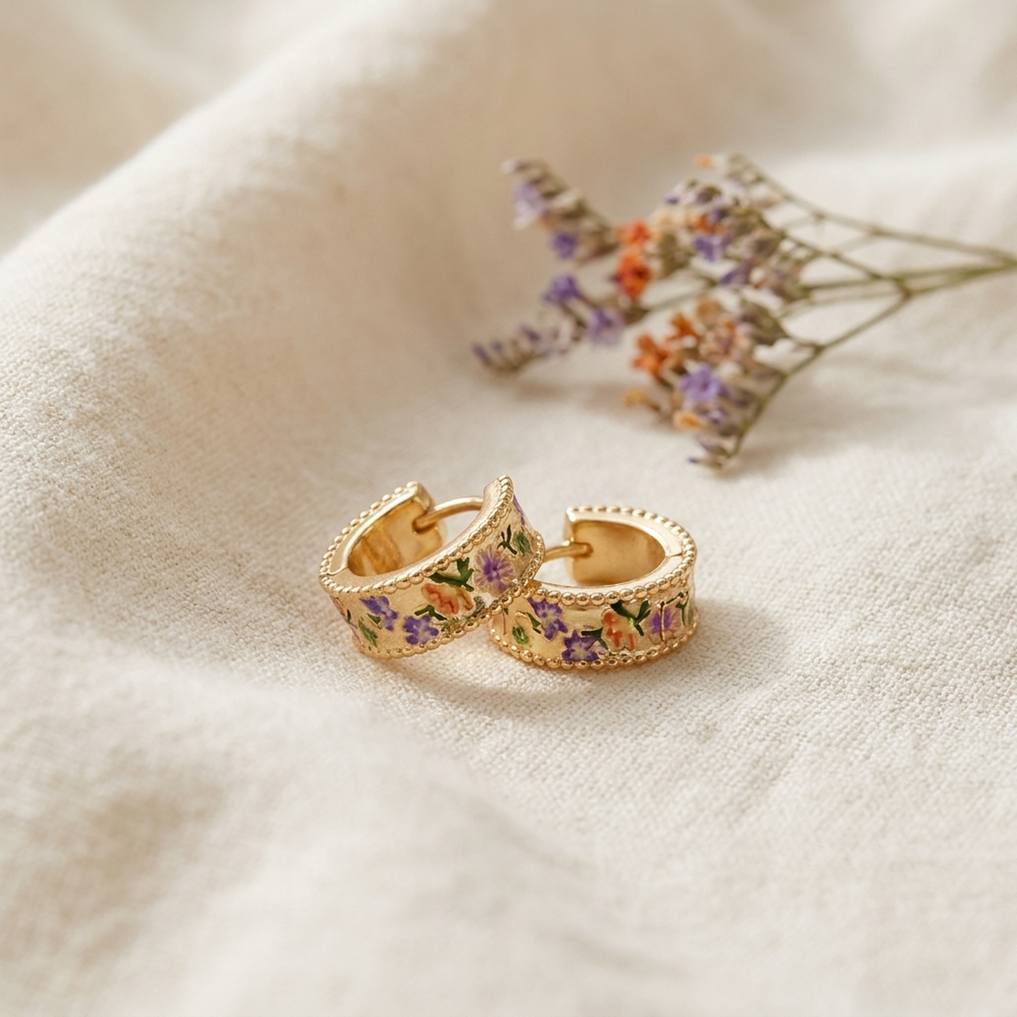 Folksy Floral Gold Huggie Earrings styled on cream linen with dried flowers