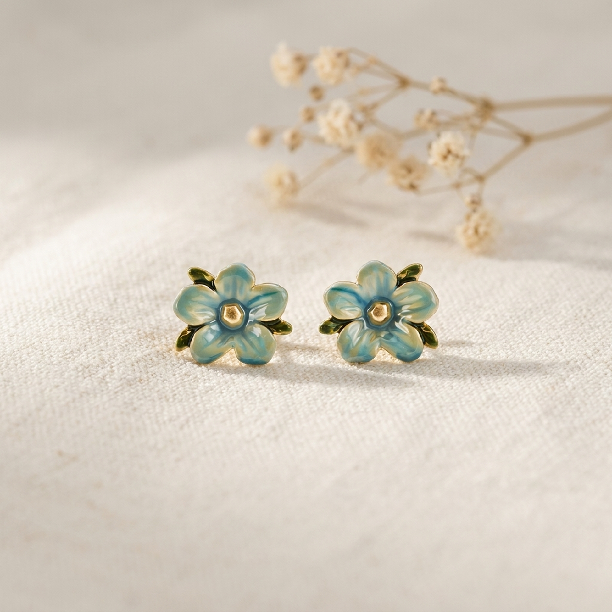Forget Me Not Stud Earrings styled on cream linen with dried flowers