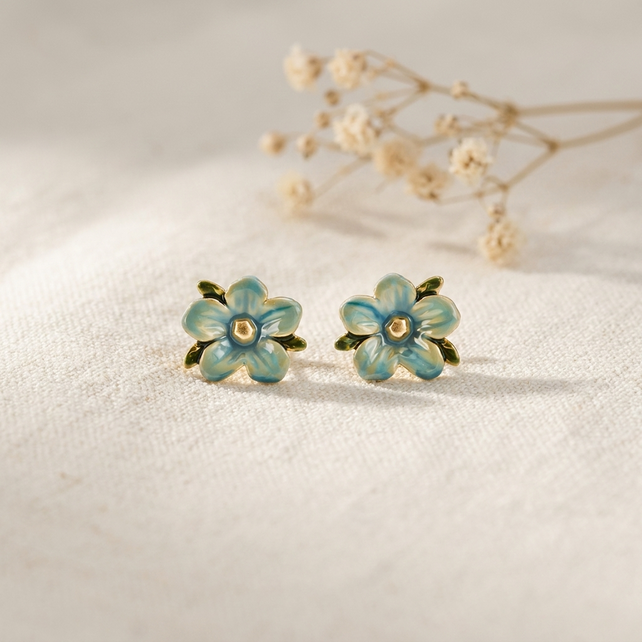 Forget Me Not Stud Earrings styled on cream linen with dried flowers