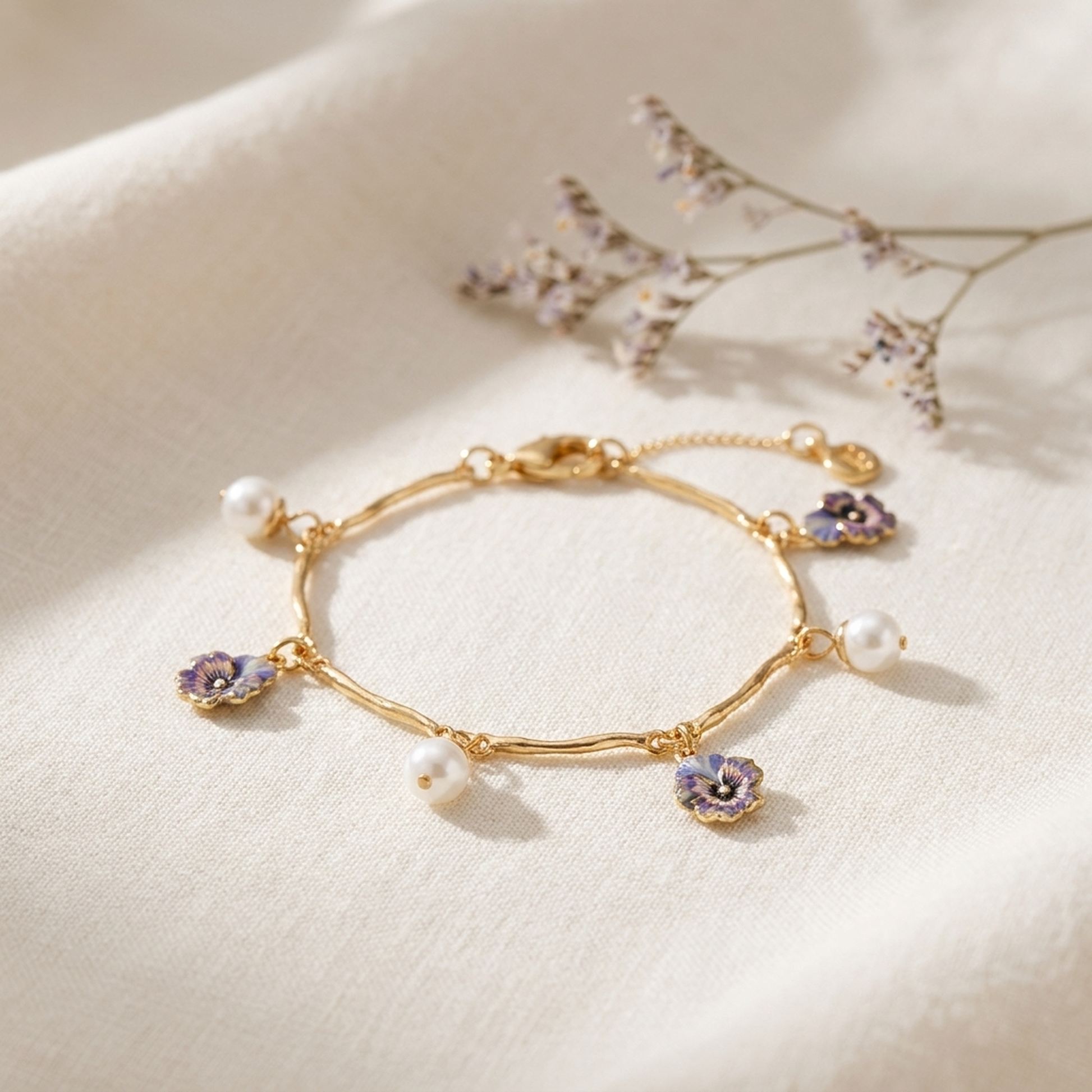 Pansy Pearl Gold Charm Bracelet styled on cream linen with dried flowers