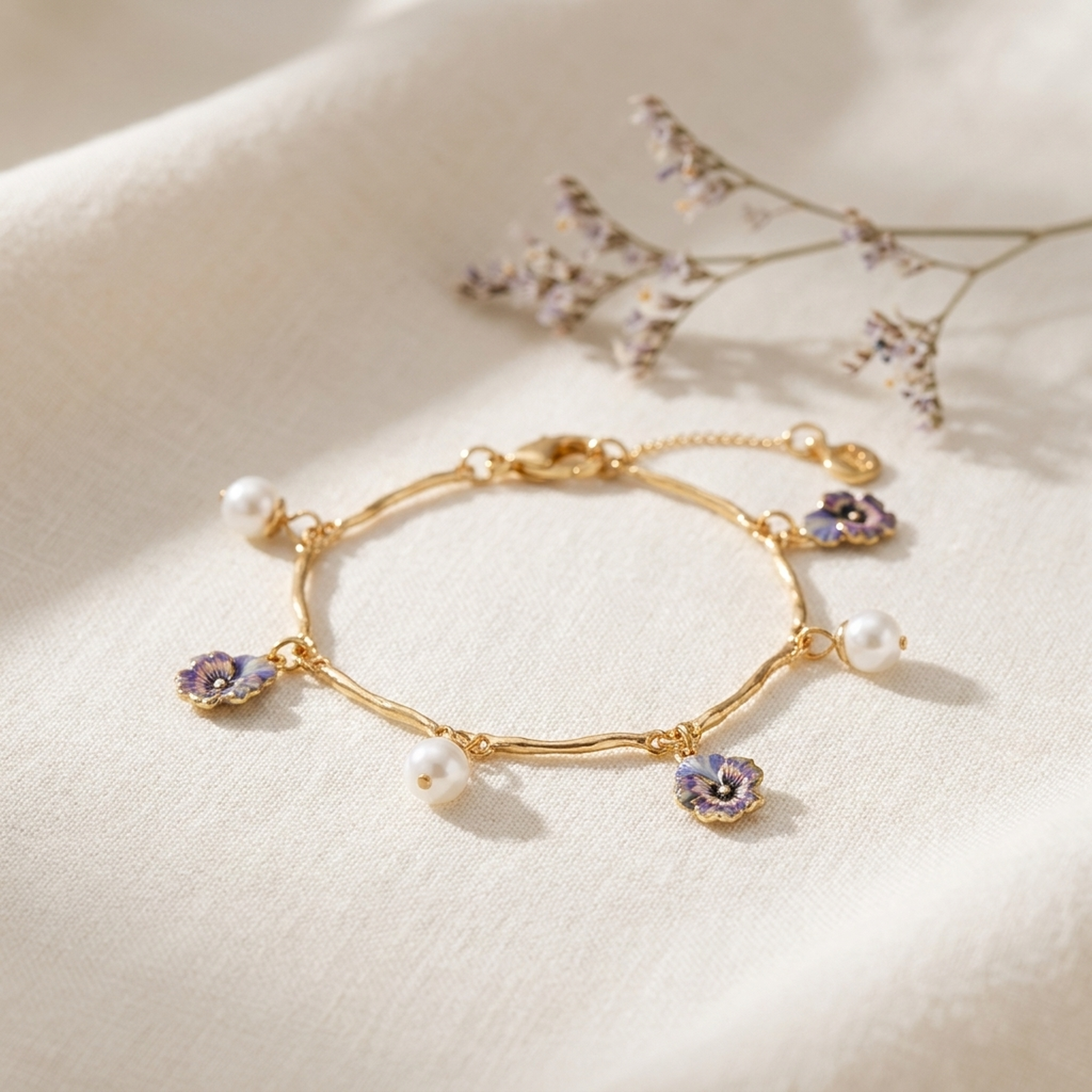 Pansy Pearl Gold Charm Bracelet styled on cream linen with dried flowers