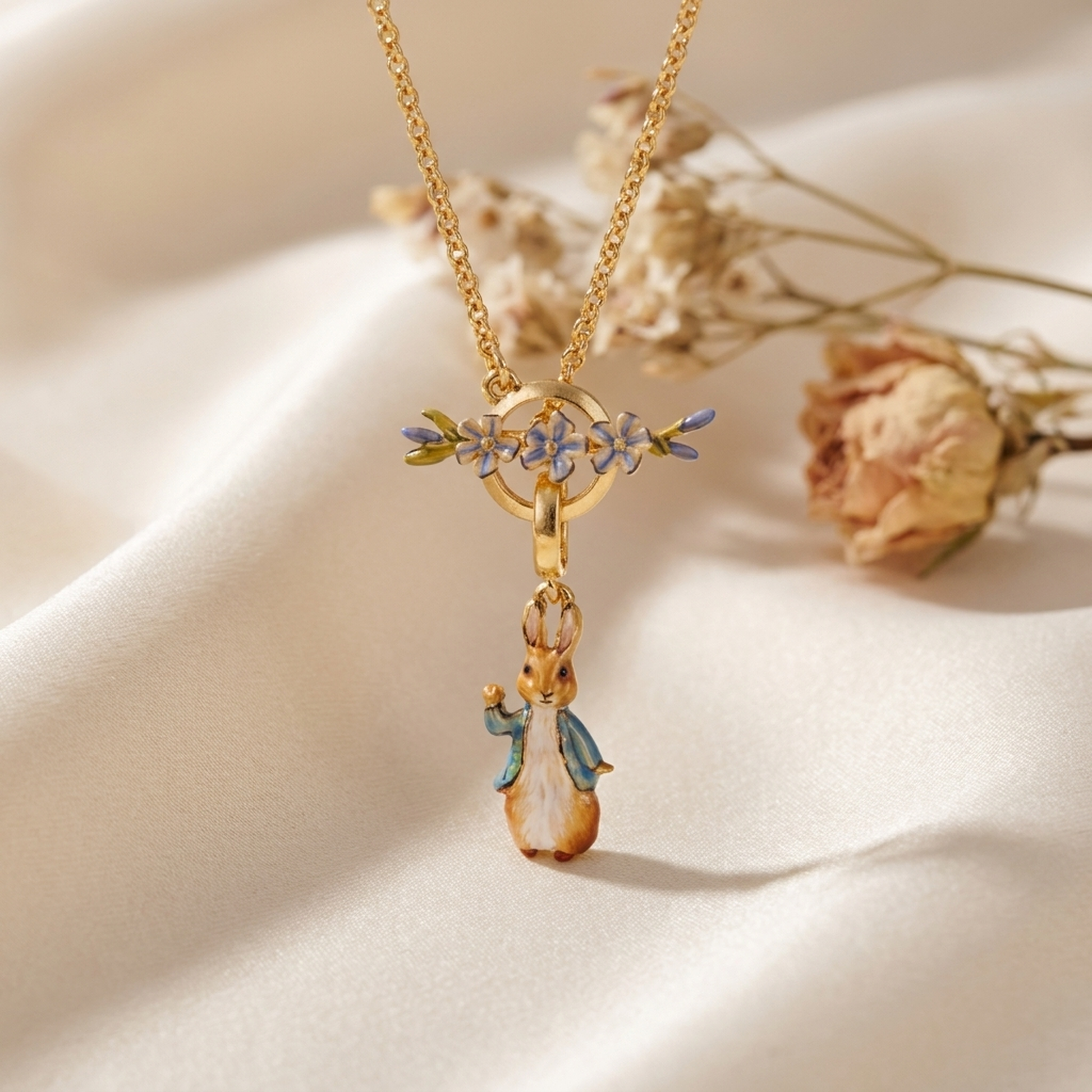 Peter Rabbit Forget-Me-Not Toggle Necklace draped on soft cream fabric with dried flowers