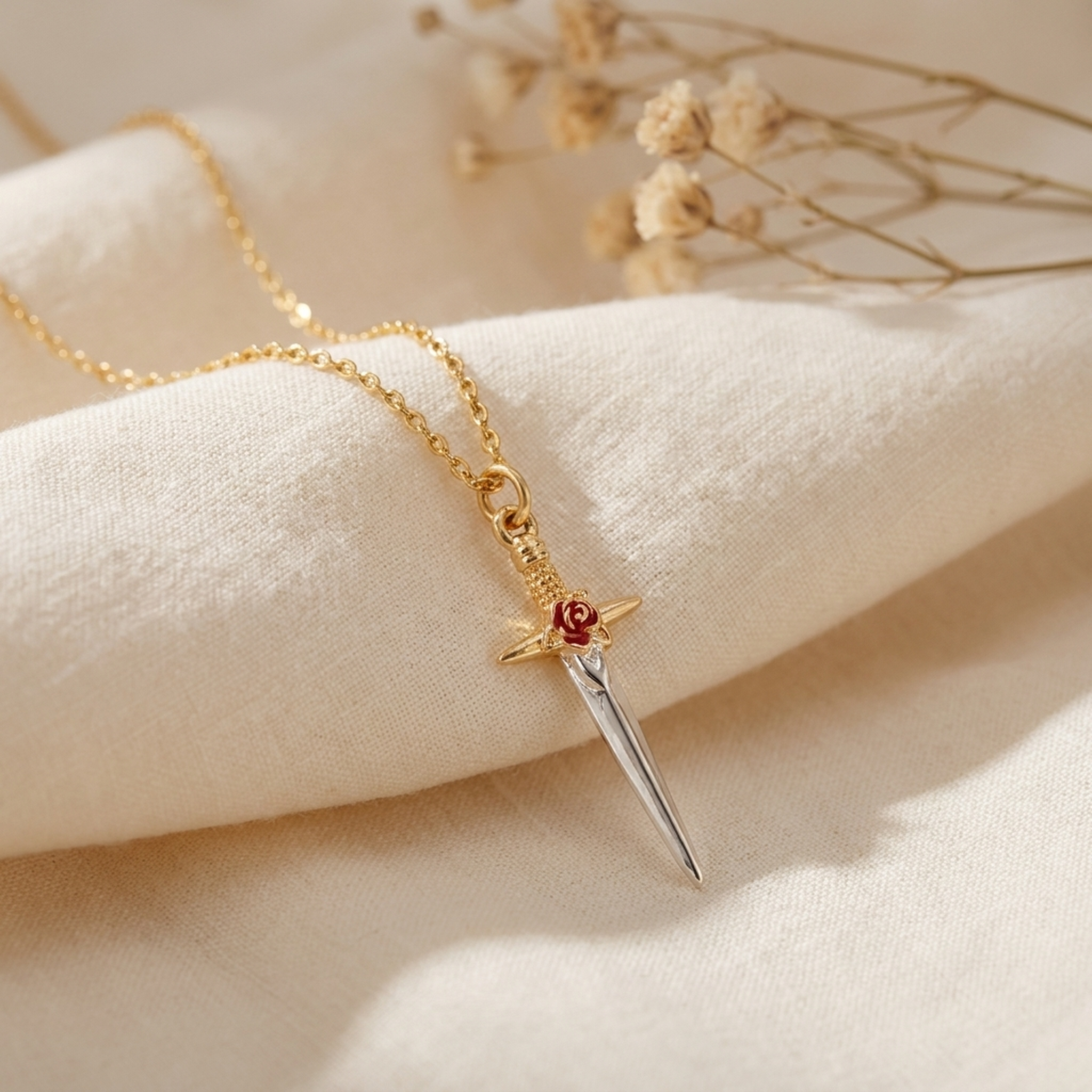 Rose Dagger Necklace draped on soft cream fabric with dried flowers