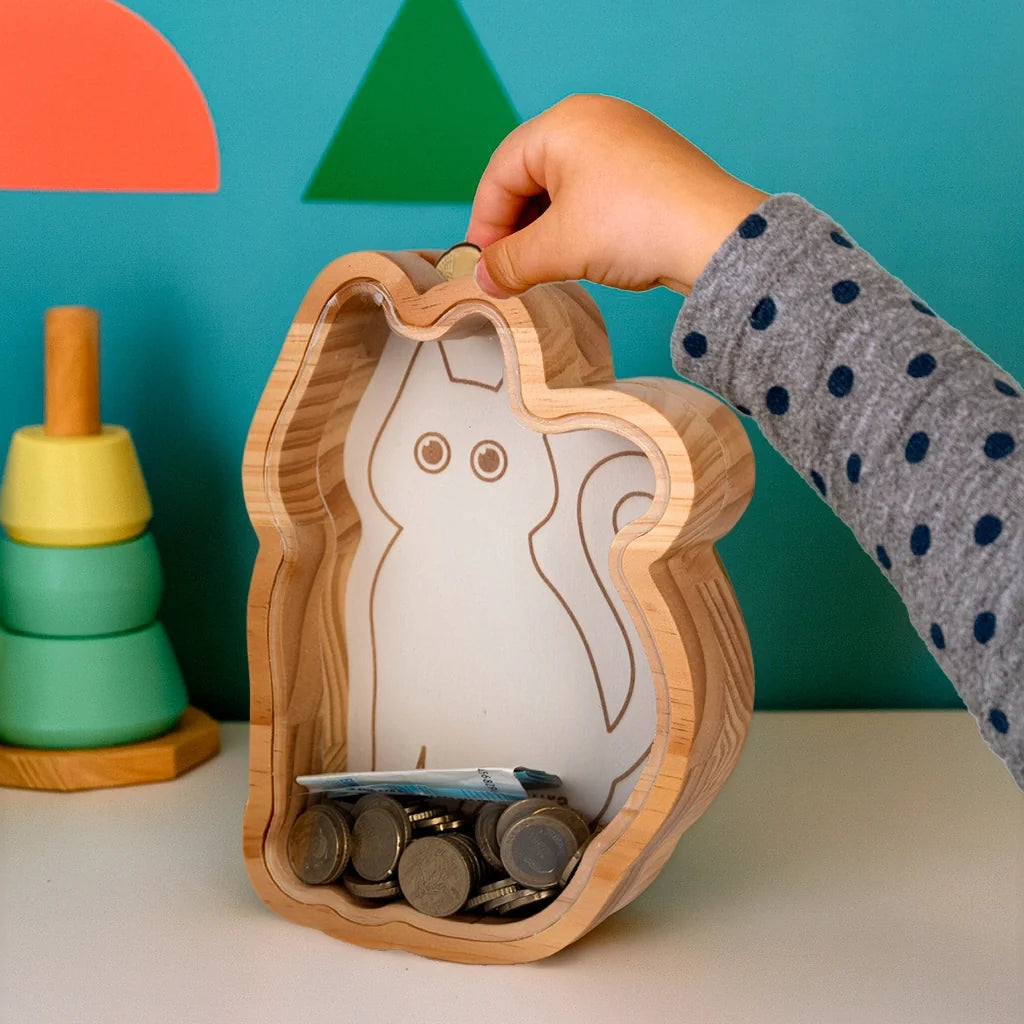 Child posting a coin into the cat money box beside stacking toys