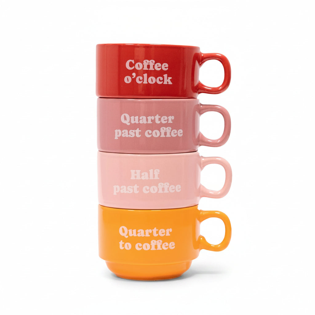 Four stacked ceramic mugs in red, pink and orange with coffee time slogans