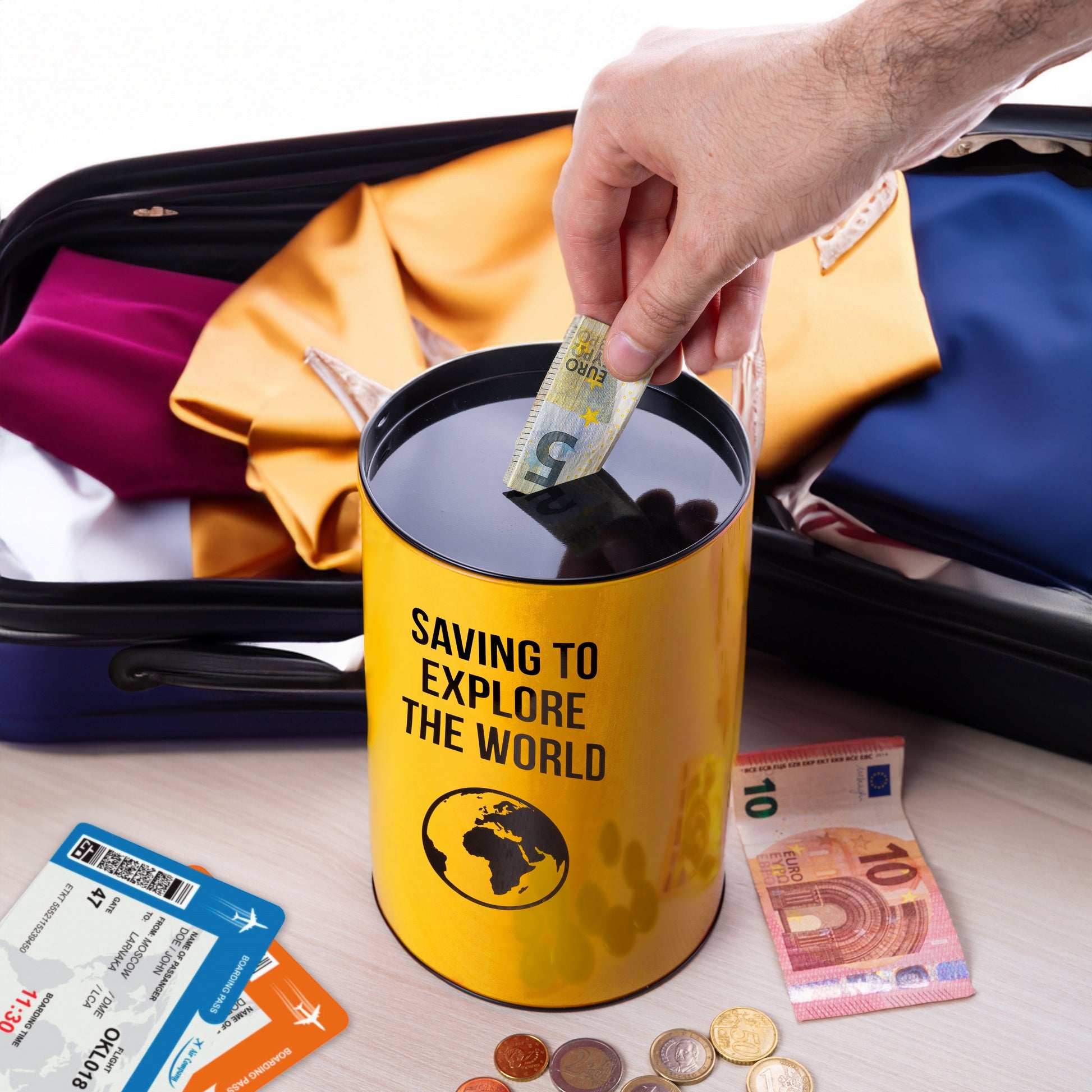 Yellow money tin packed in an open suitcase with cards and currency