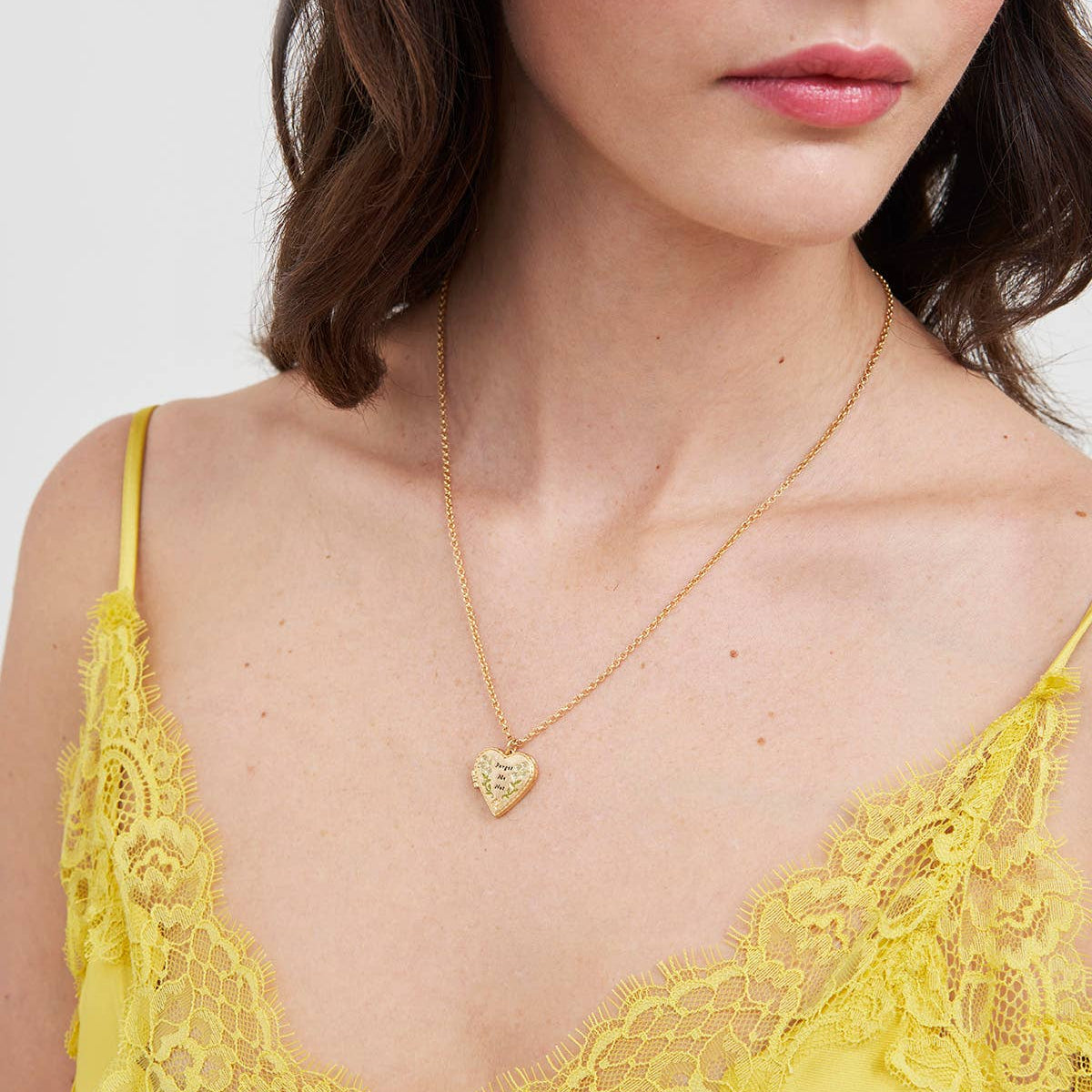 Model wearing floral heart gold locket necklace with yellow lace top.