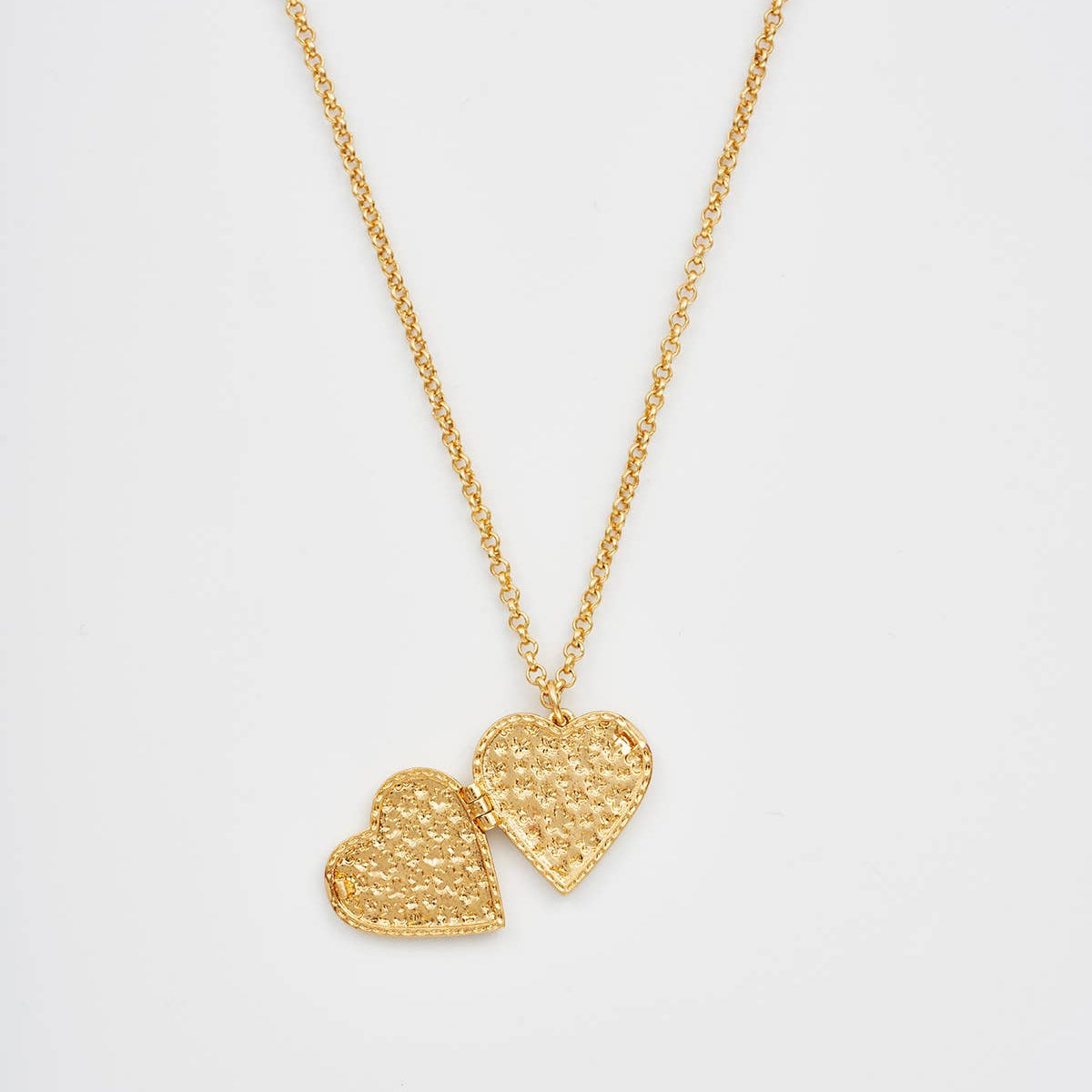 Open floral heart gold locket necklace showing textured interior on white background.