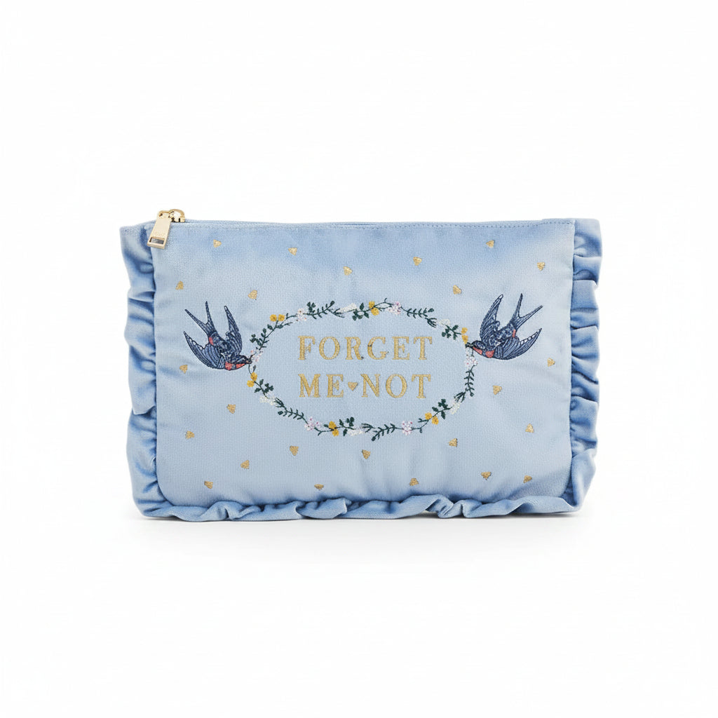 Front view of embroidered blue velvet pouch on white background