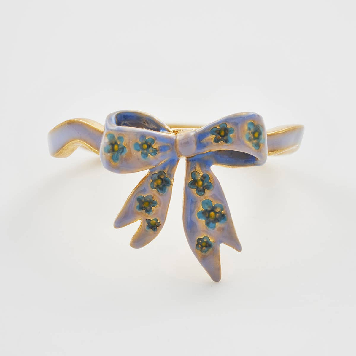 Close-up of blue enamel bow detail on gold Forget-Me-Not ring.