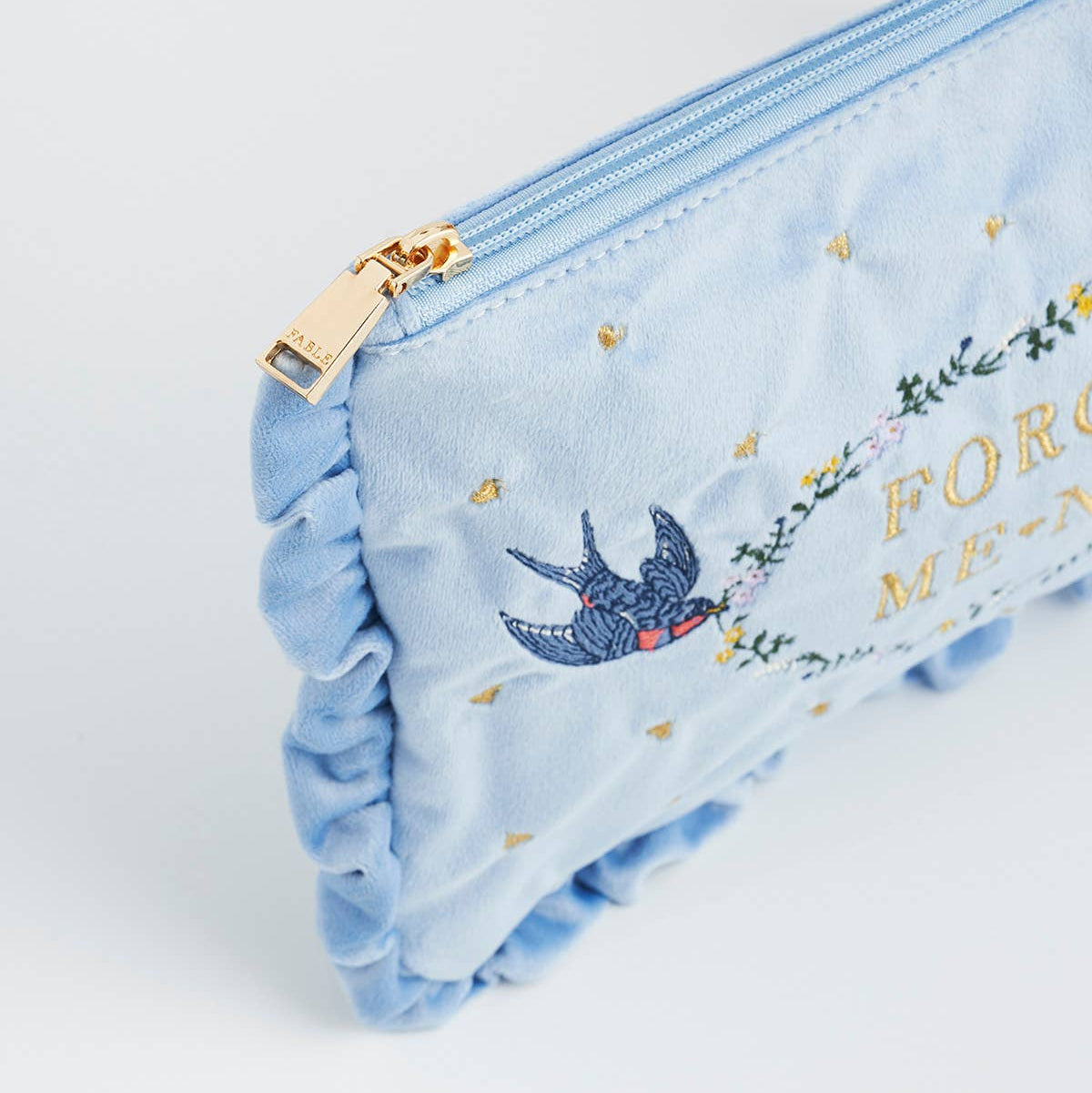 Close-up of zip and ruffle on blue velvet pouch