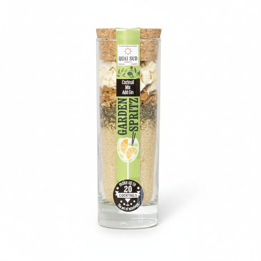 Garden Spritz Cocktail Mix by Quai Sud in tall glass bottle with cork lid and green label, layered with lemon peel, mint, apple pieces and cane sugar.