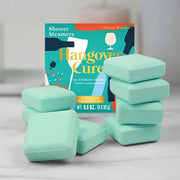 Hangover Cure shower steamers stacked beside their teal box on a marble shelf