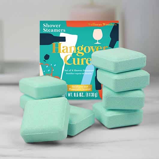 Hangover Cure shower steamers stacked beside their teal box on a marble shelf