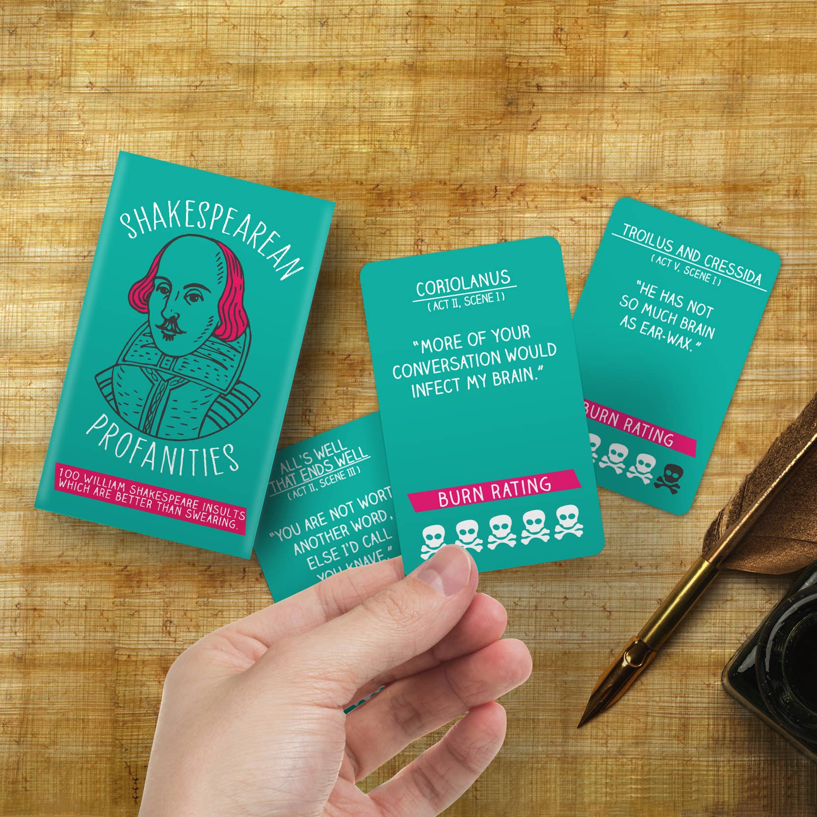 Shakespearean Profanities cards held in hand over parchment and quill