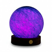 AstraGlass mini light glowing purple and blue on walnut base on books
