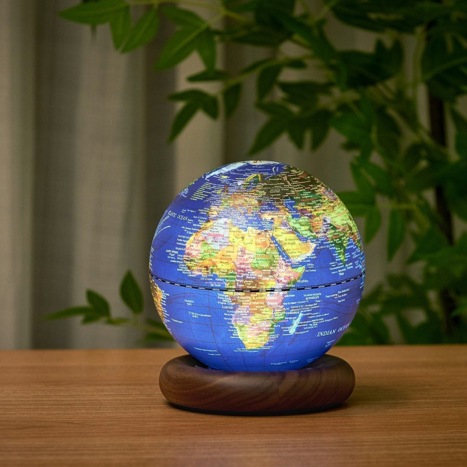 Lit dark blue globe light showing Africa and Europe on a wooden table
