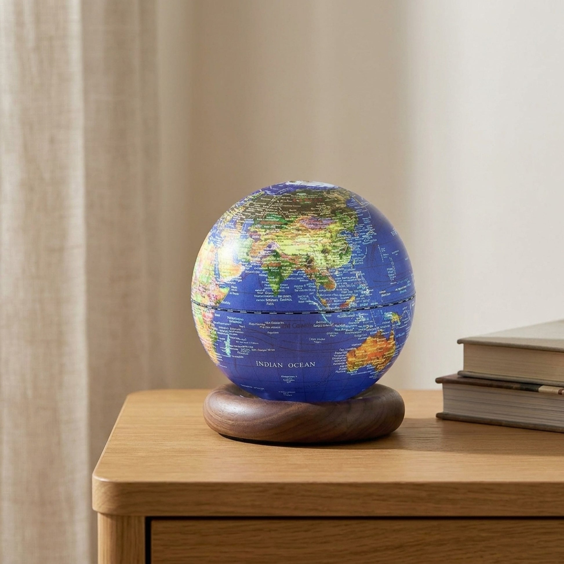 Dark blue AtlasGlobe light glowing on an oak side table beside books