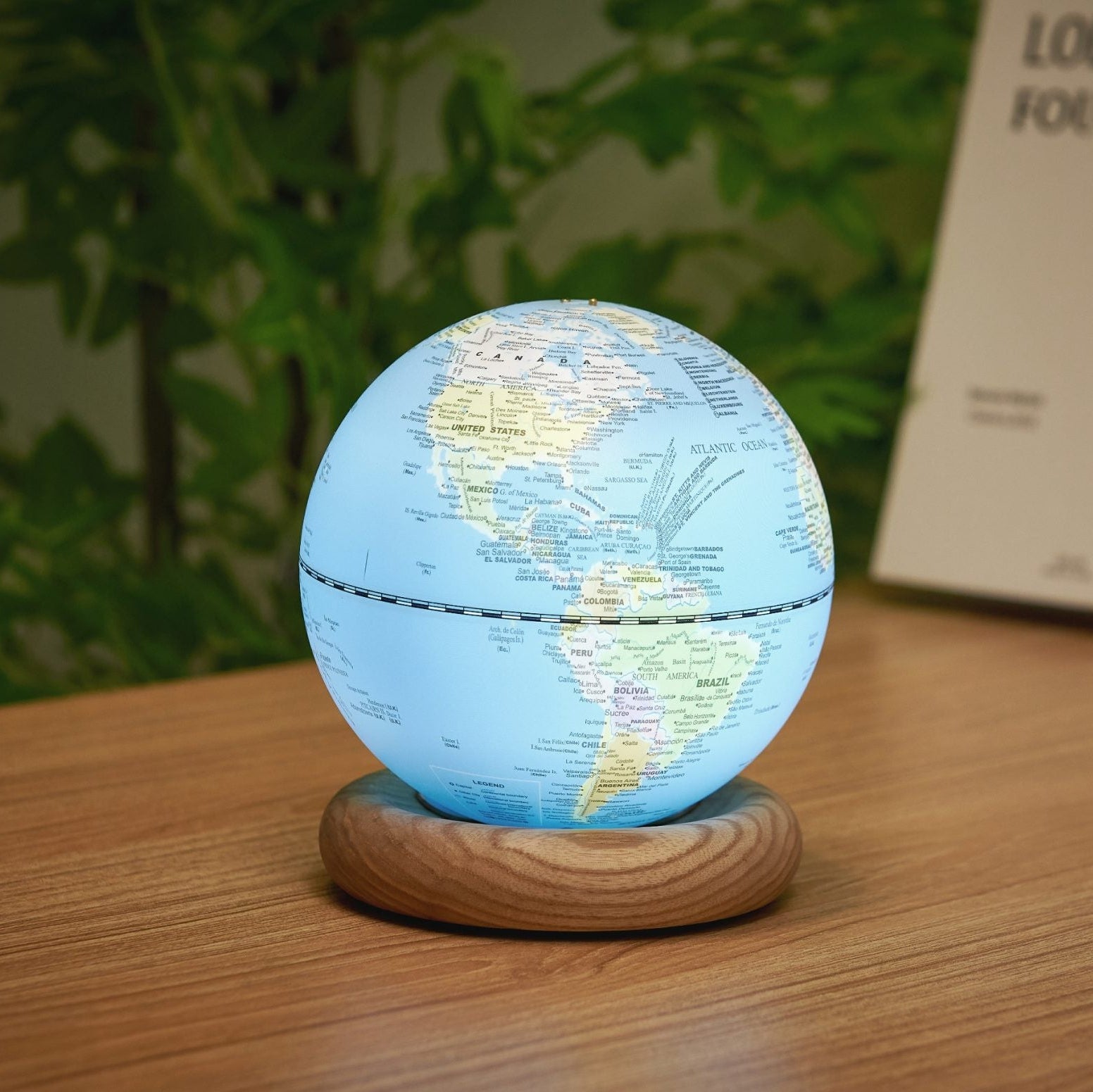 Sky blue globe light showing the Americas, lit on a wooden desk