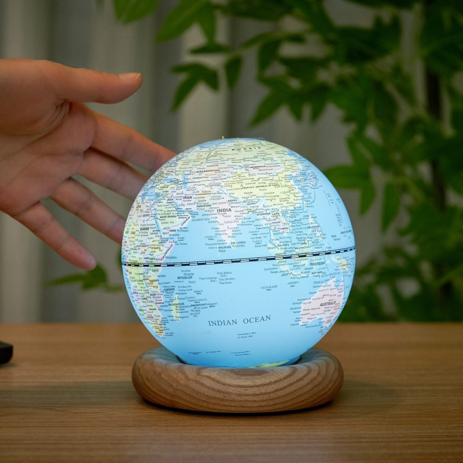 Hand reaching to tap the top of the lit sky blue globe light