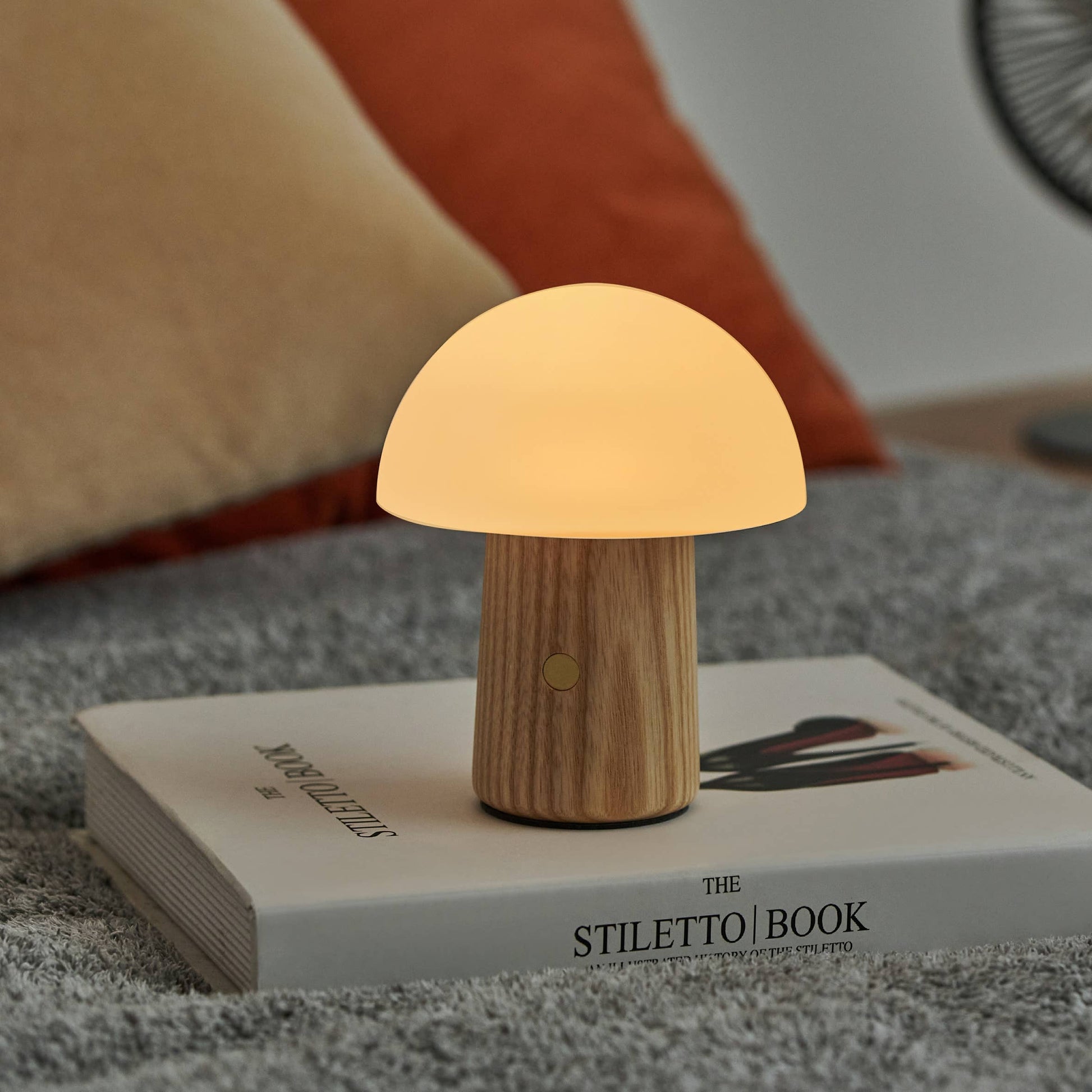 Ash Alice Mushroom Lamp glowing warm white on a fashion book