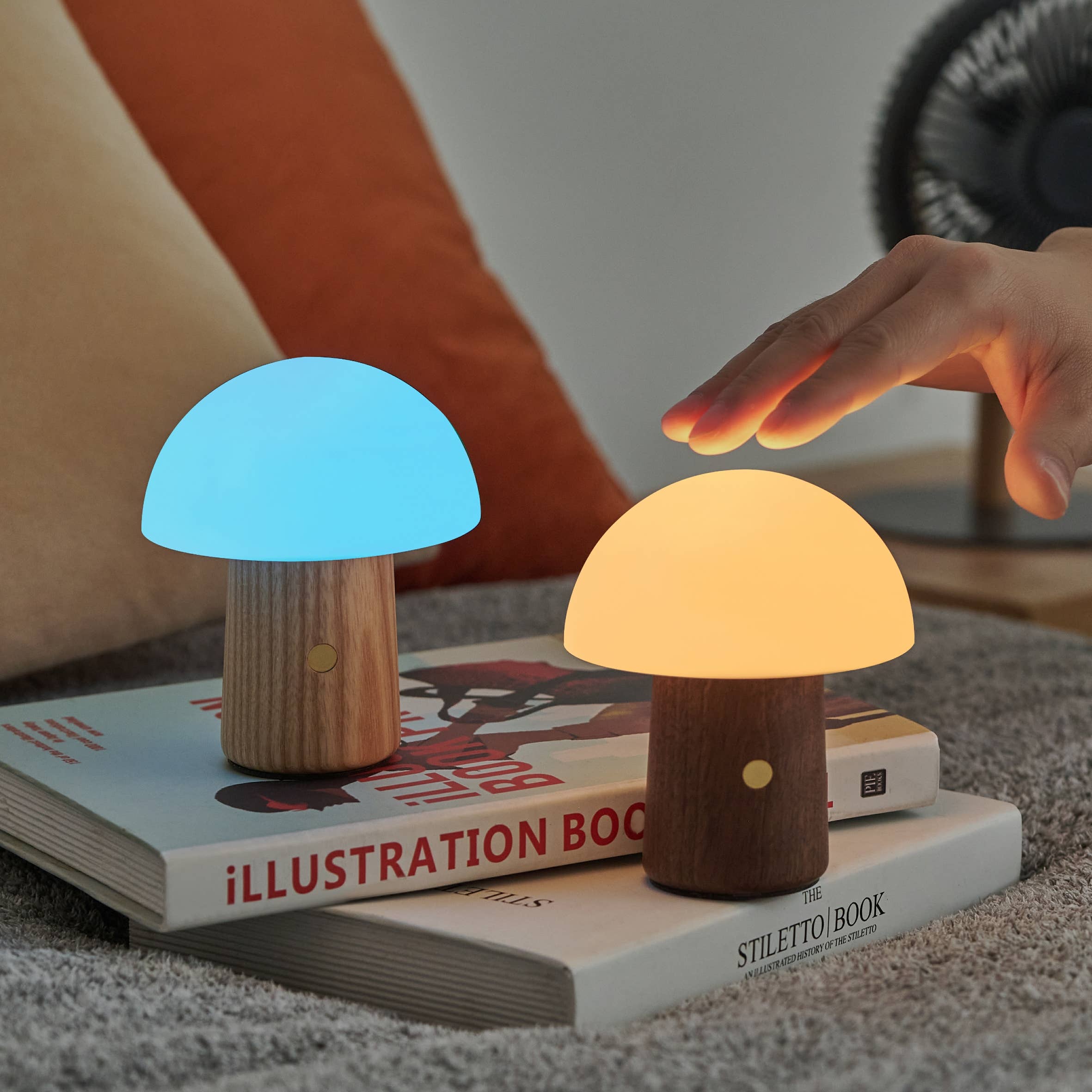 Alice Mushroom Lamp pair glowing blue and warm white beside reaching hand