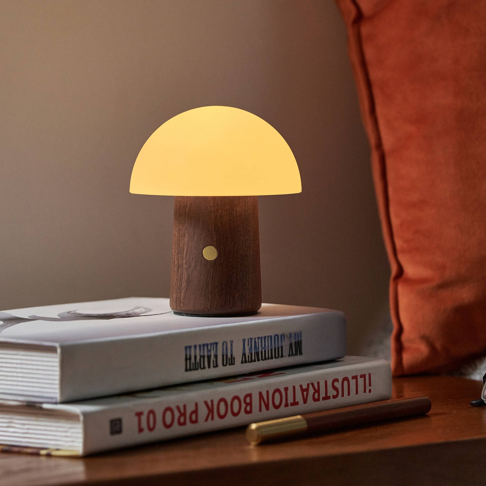 Mini Alice Mushroom Lamp in walnut glowing warm white on bedside books