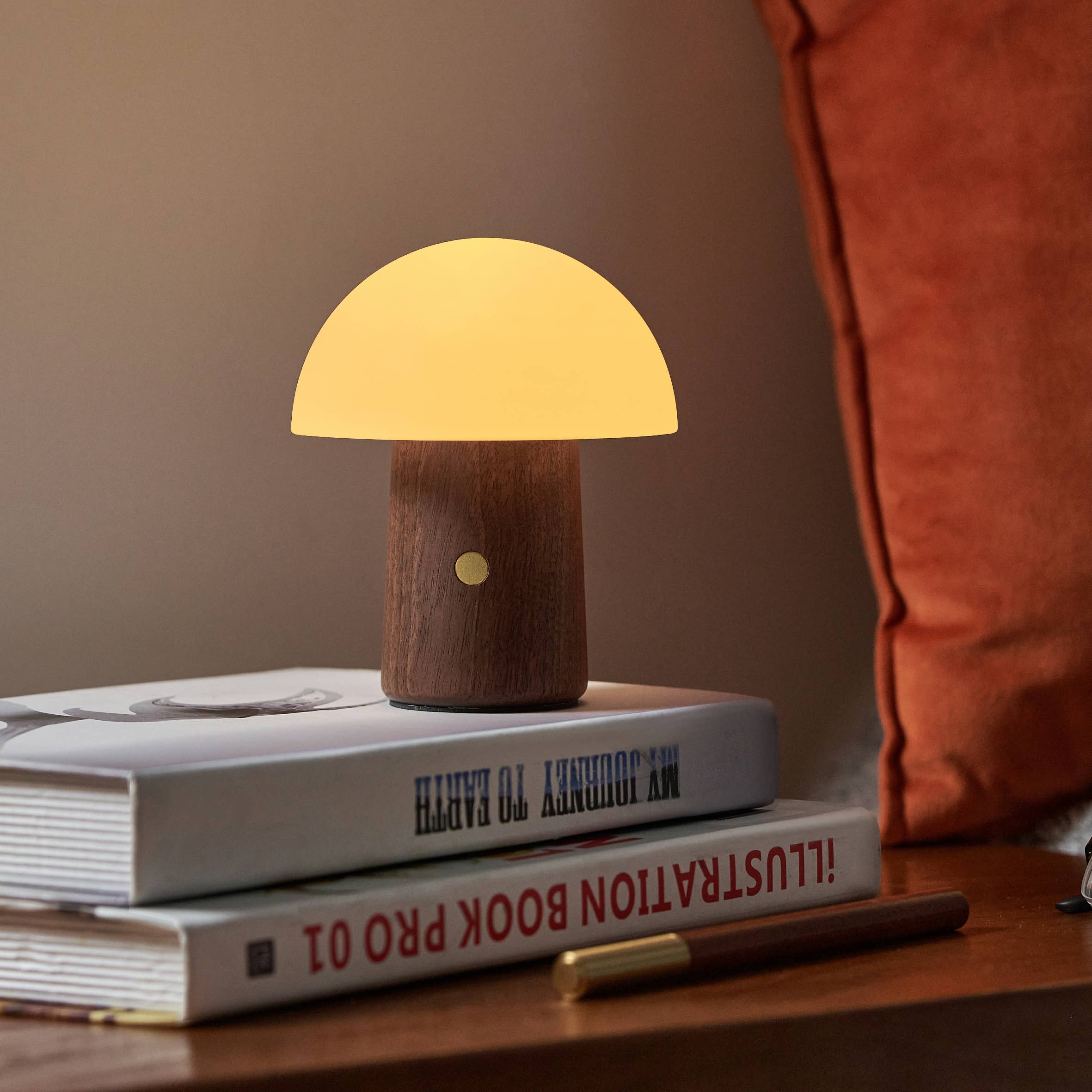 Mini Alice Mushroom Lamp in walnut glowing warm white on bedside books