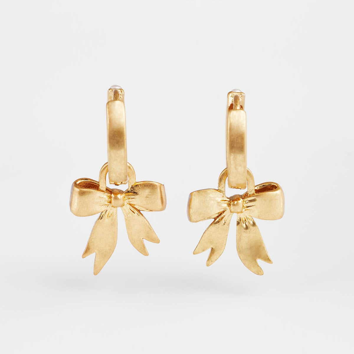 Back view of the gold bow charms showing the metal finish and shape.